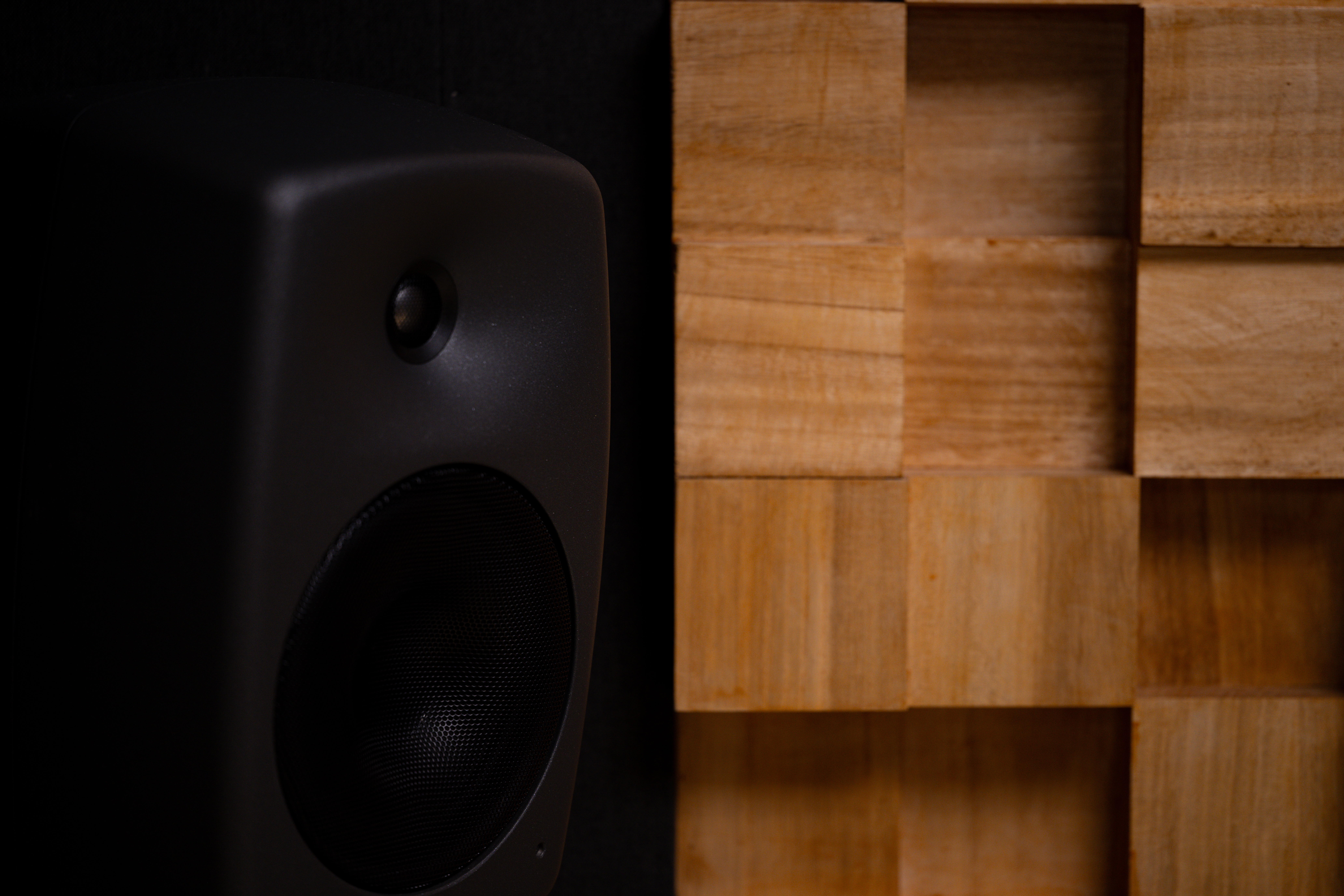 a black speaker positioned next to a wooden geomet 88372a0243bcec5eed4c