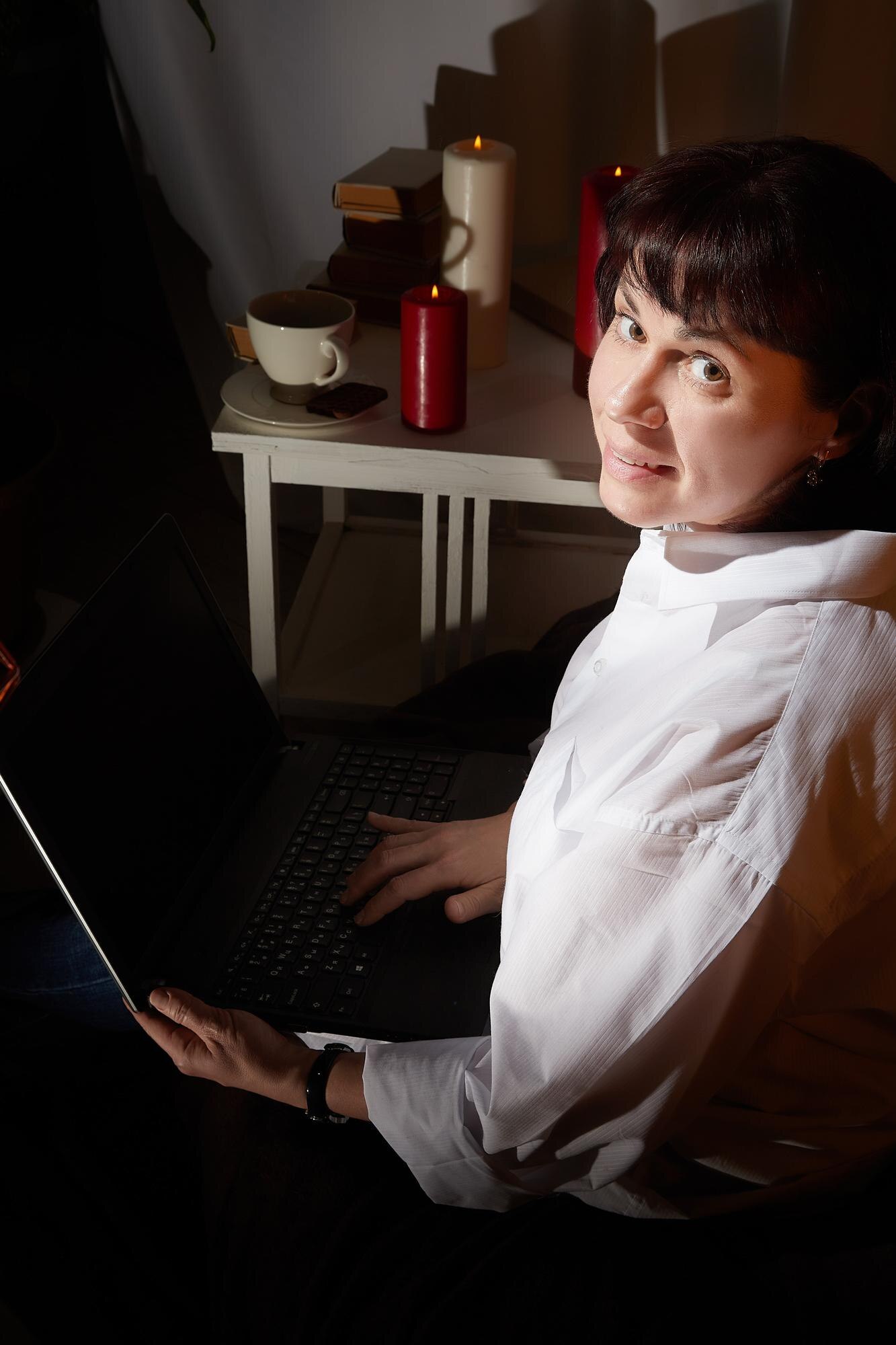 a girl in a white shirt with a laptop in a dark ro 7b02e2dc75ef8b2318e7
