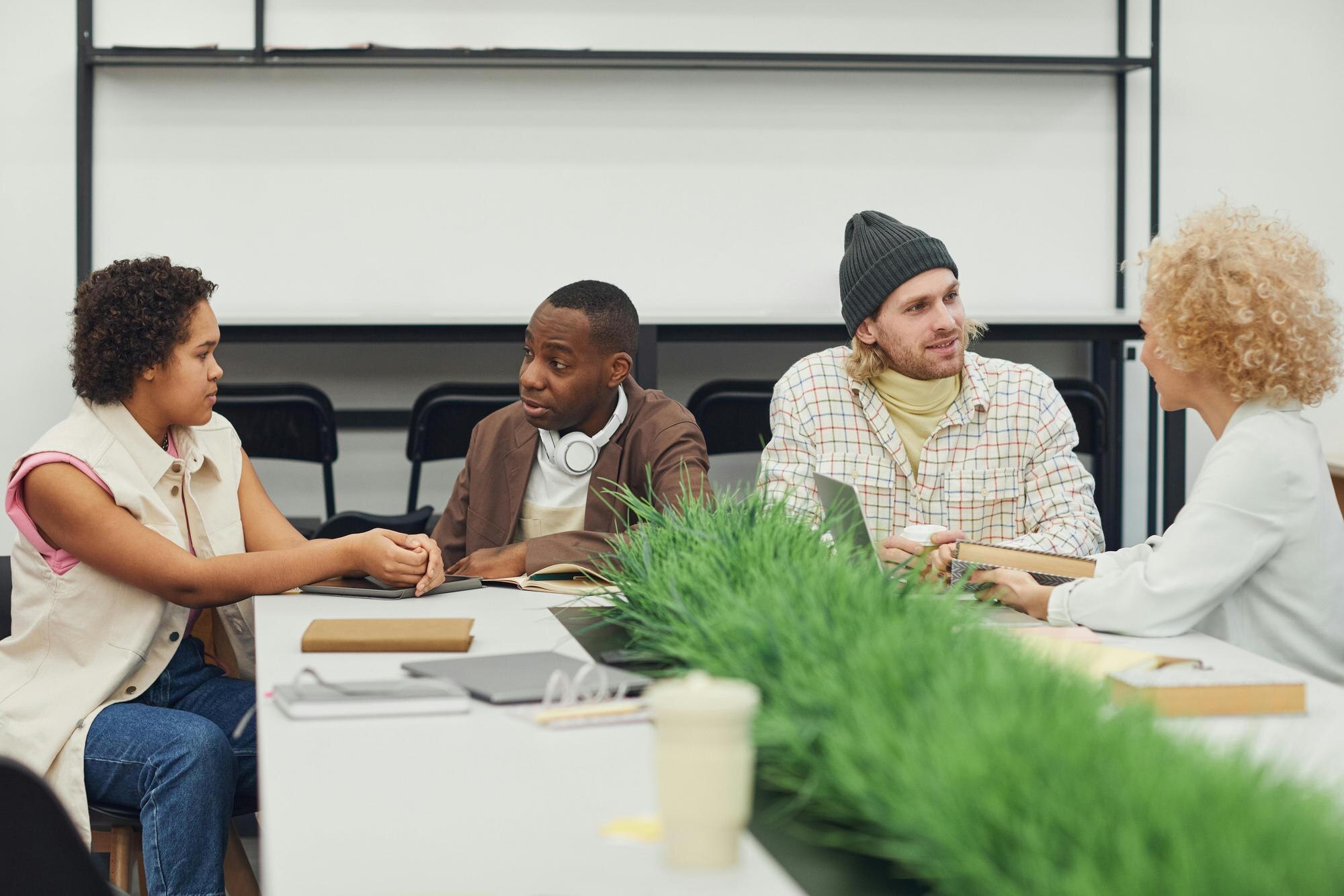 a group of people sit around a table with a laptop de5441d4eb801e276f25