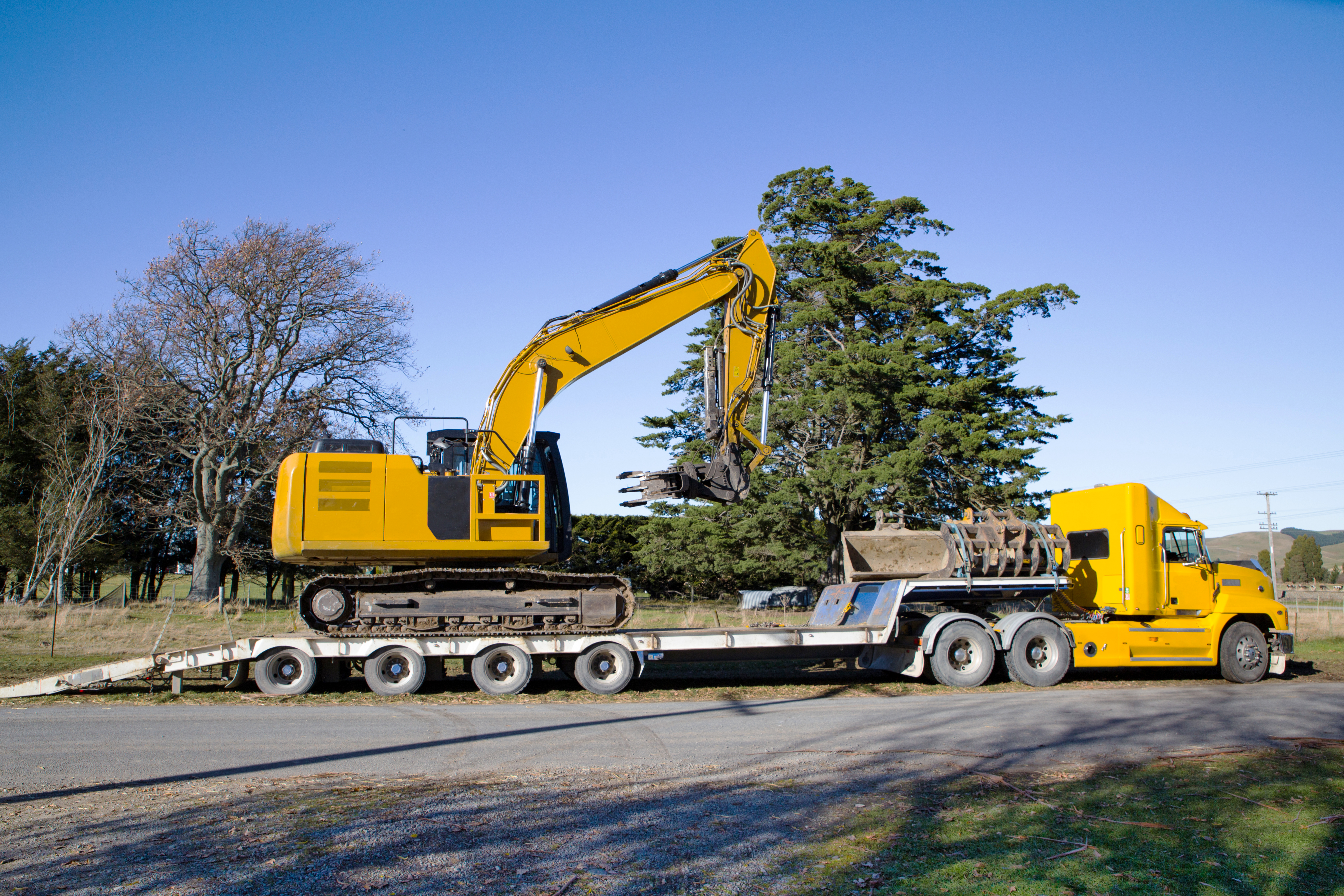 a large yellow digger is loaded onto a truck and t 8fdcb13b04ded3fc7a22