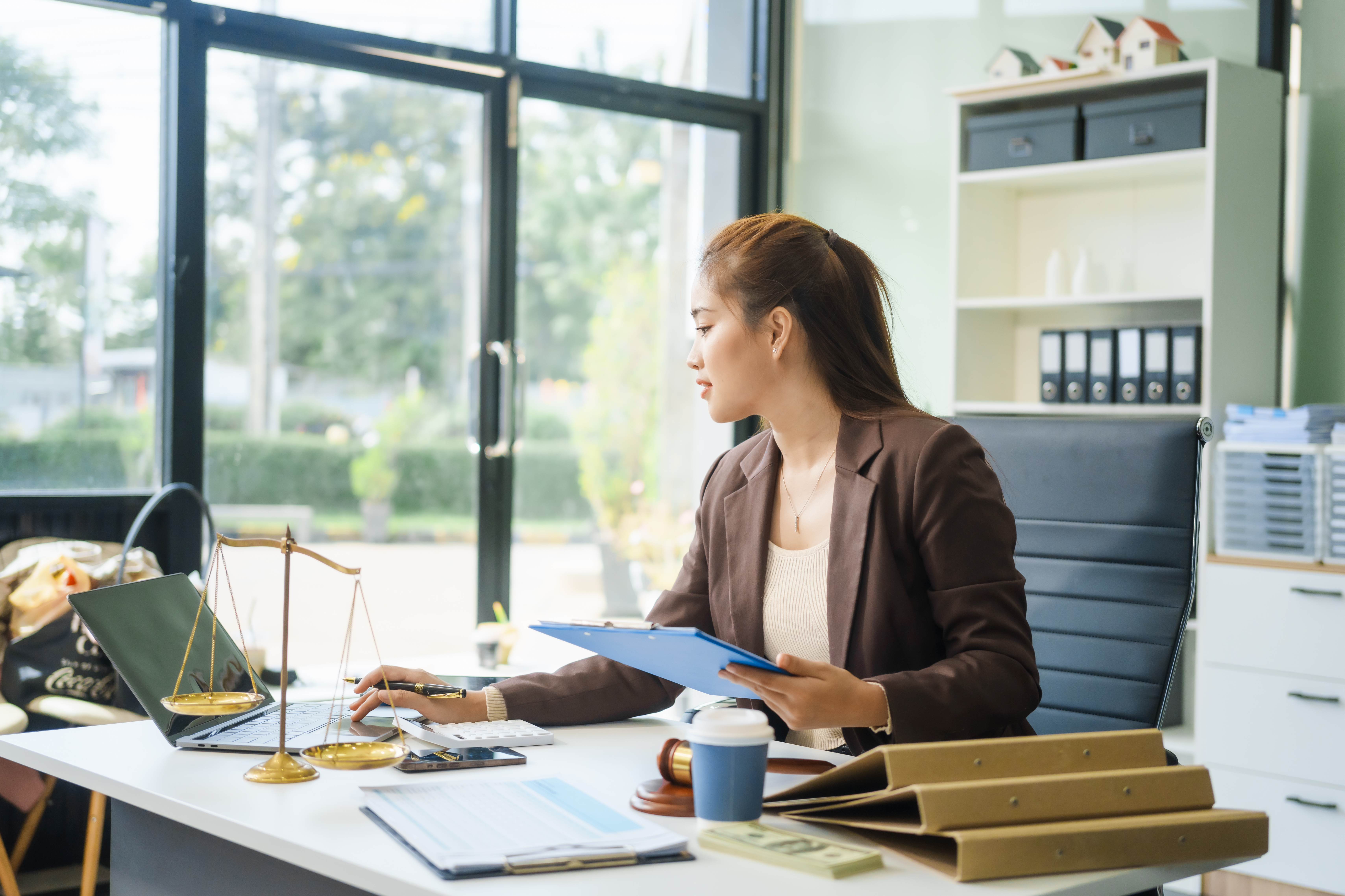 Young female lawyer at desk with laptop, legal scales, and documents, emphasizing legal foundation for small business success.