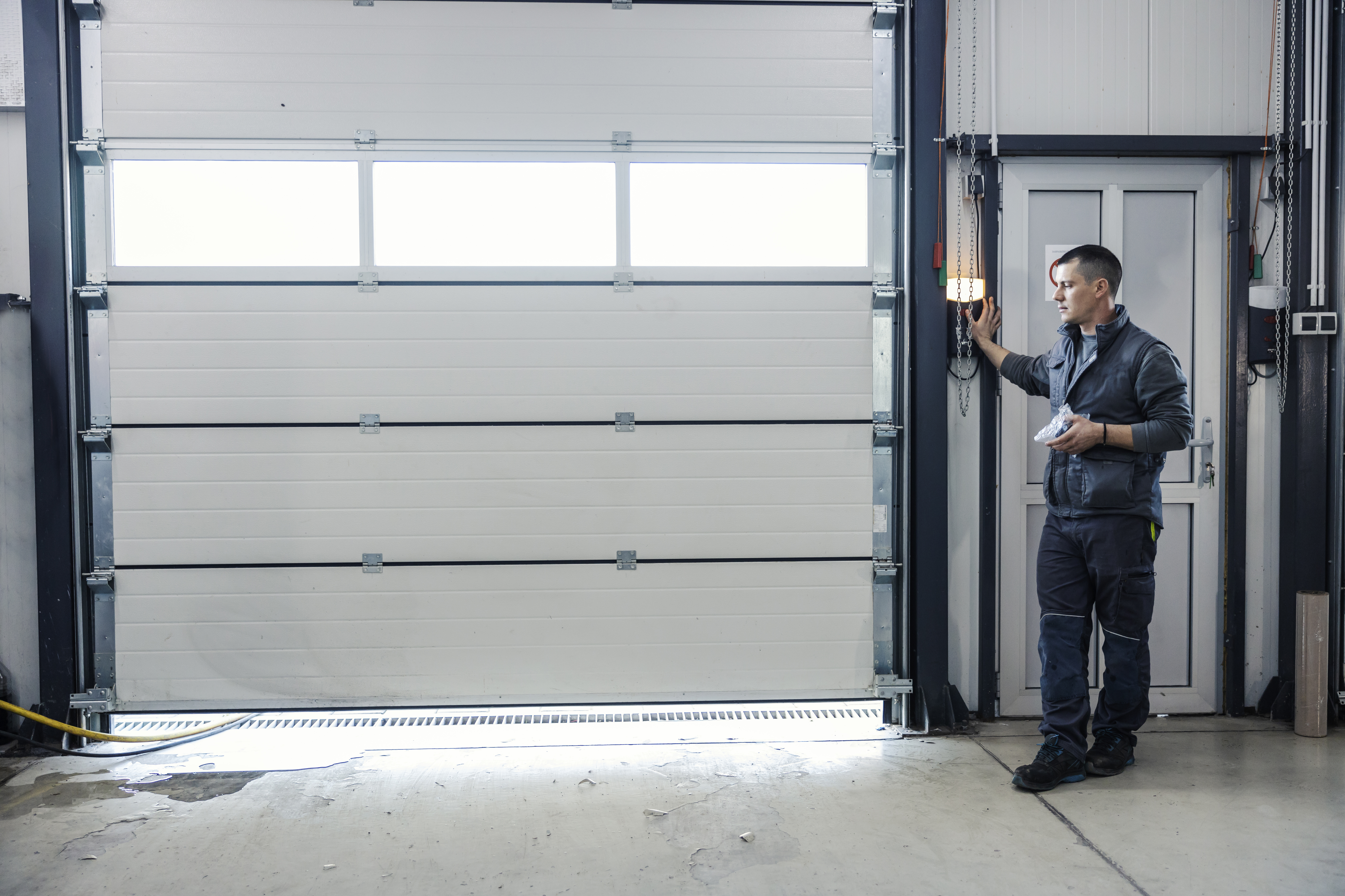 Unlock Savings and Longevity: The Power of Routine Garage Door Maintenance 2 an auto mechanic is opening garage door at mechani 41168f72fdc0ca3999a6