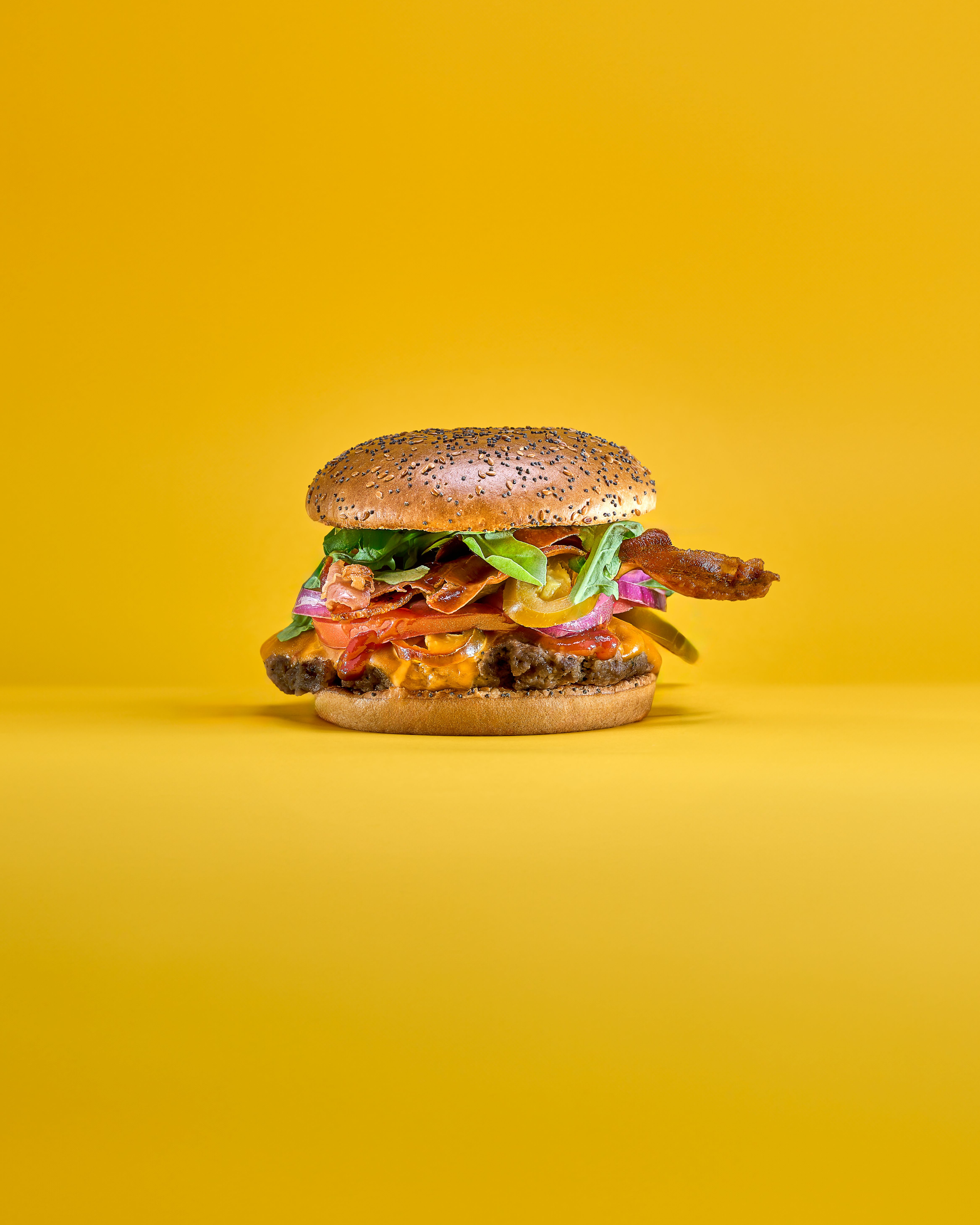 appealing hamburger stacked on a bright yellow bac afce94c229fb7d0778b6