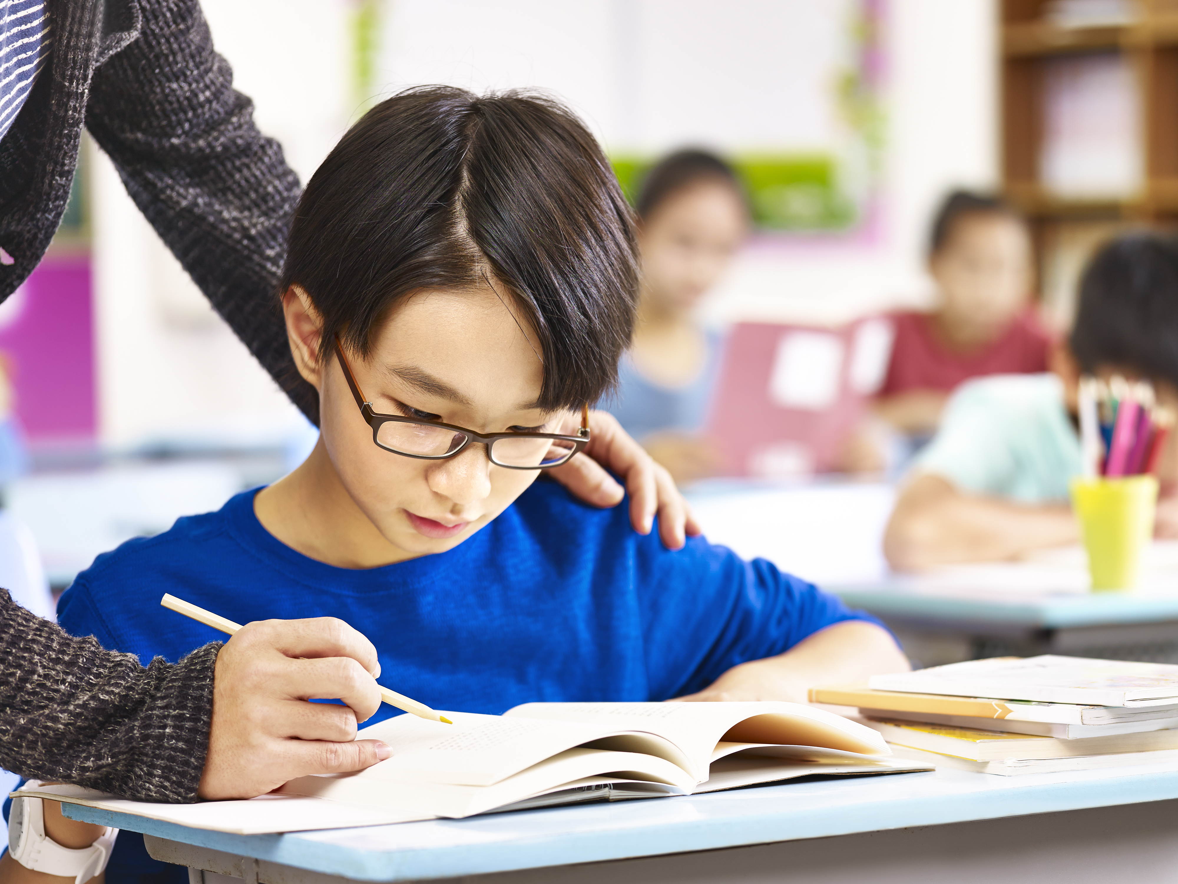 Asian Pupil Getting Help From Teacher In Class C527571eba8c08a6150a