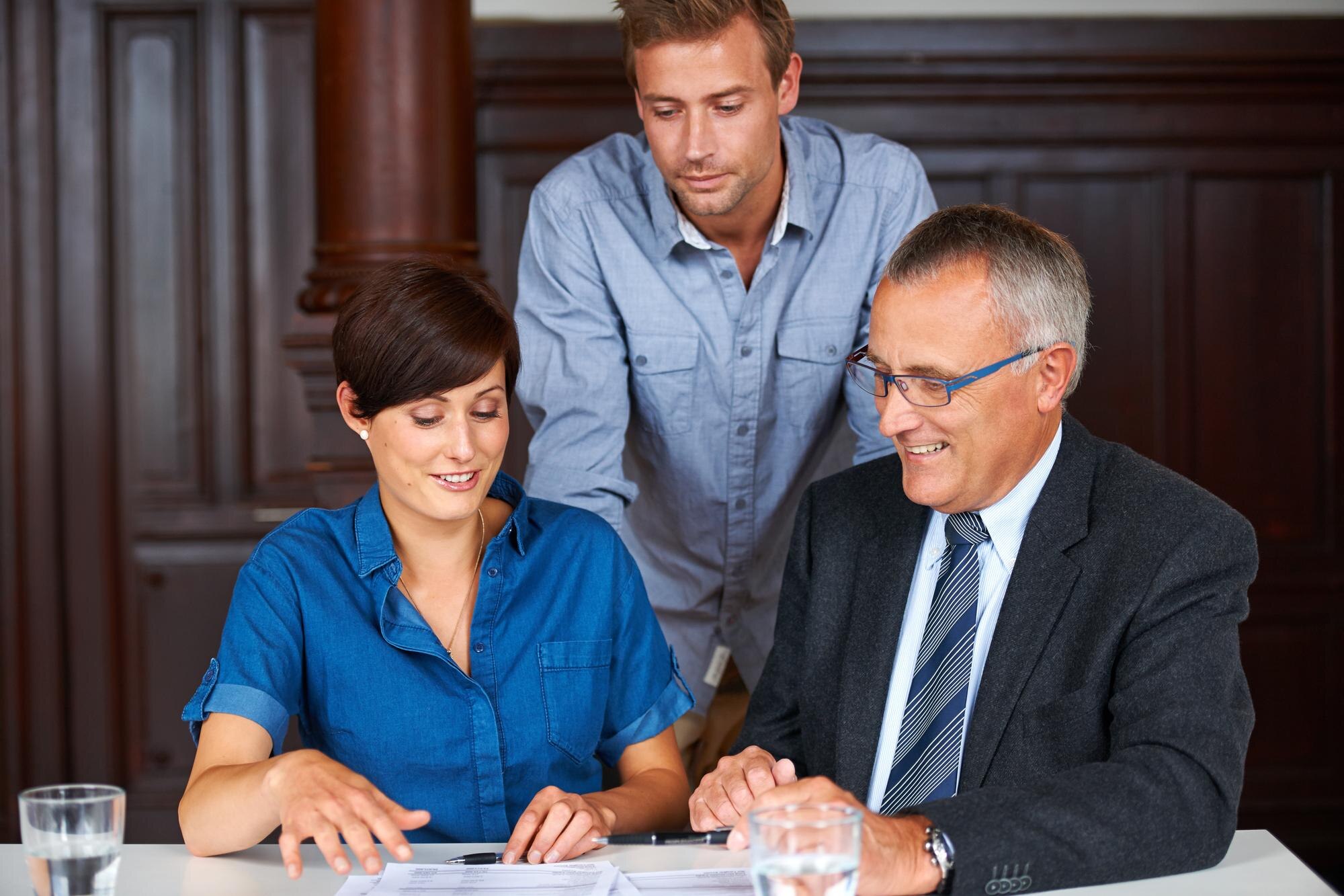 Three professionals engaged in discussion over documents, highlighting collaboration and legal consultation for military divorce matters.