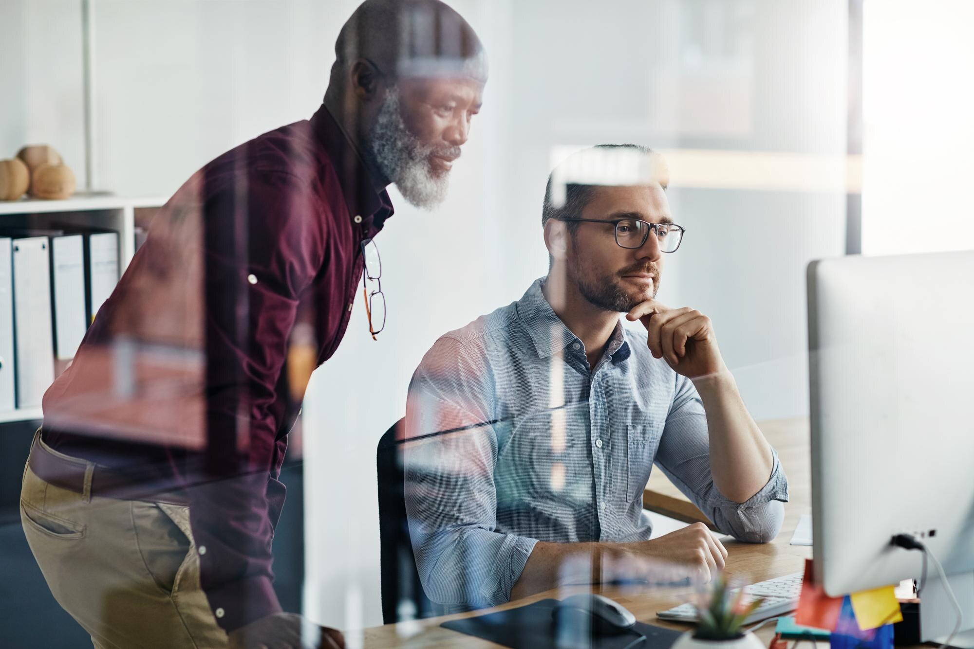 Two business professionals collaborating on a computer, discussing local SEO strategies and automated solutions for Google Business Profile management.