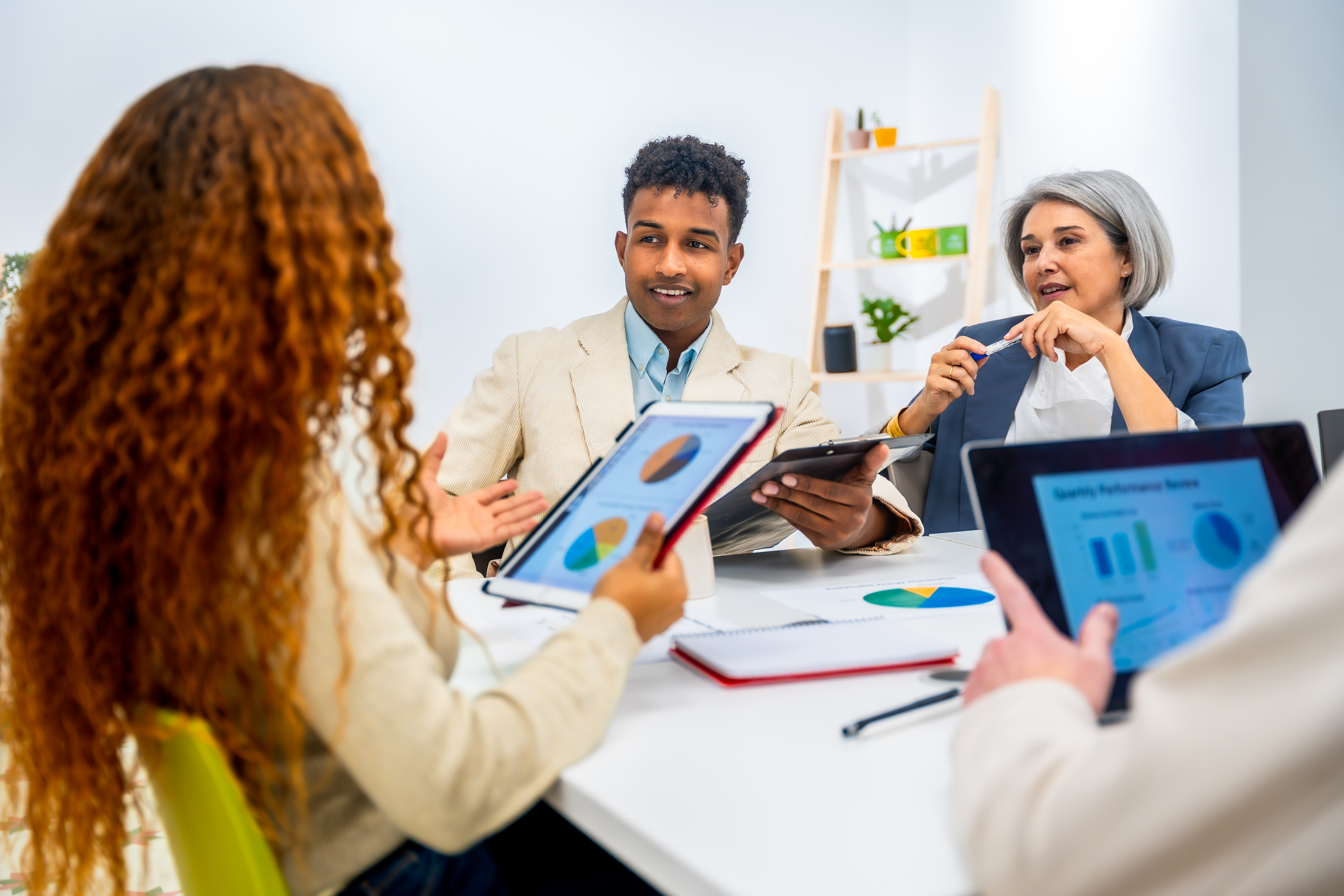 Business team engaging in discussion during an office meeting, analysing data on tablets, showcasing graphs and charts related to reputation management and customer trust.