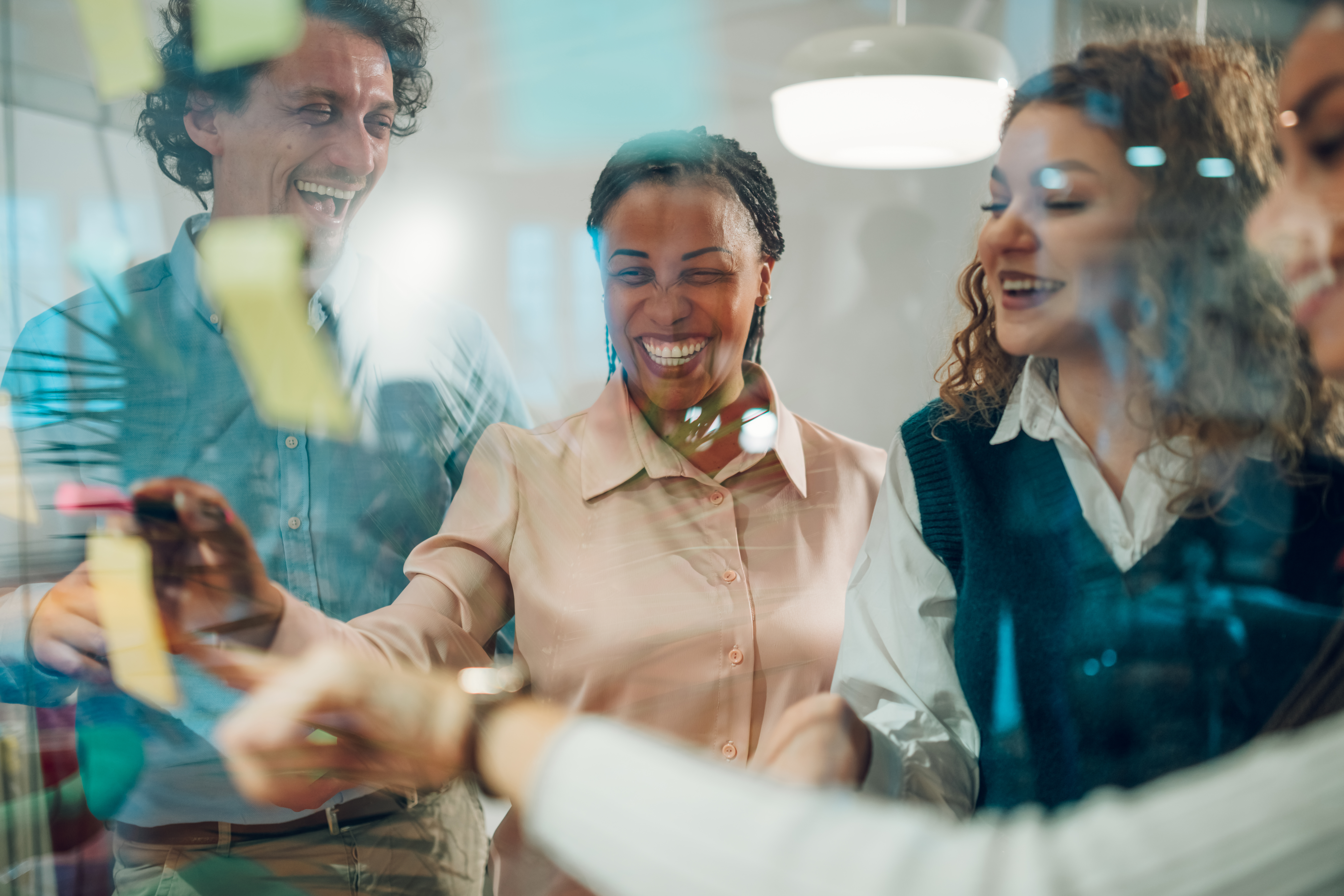 team of coworkers collaborating with dry erase markers on a glass window in a conference room
