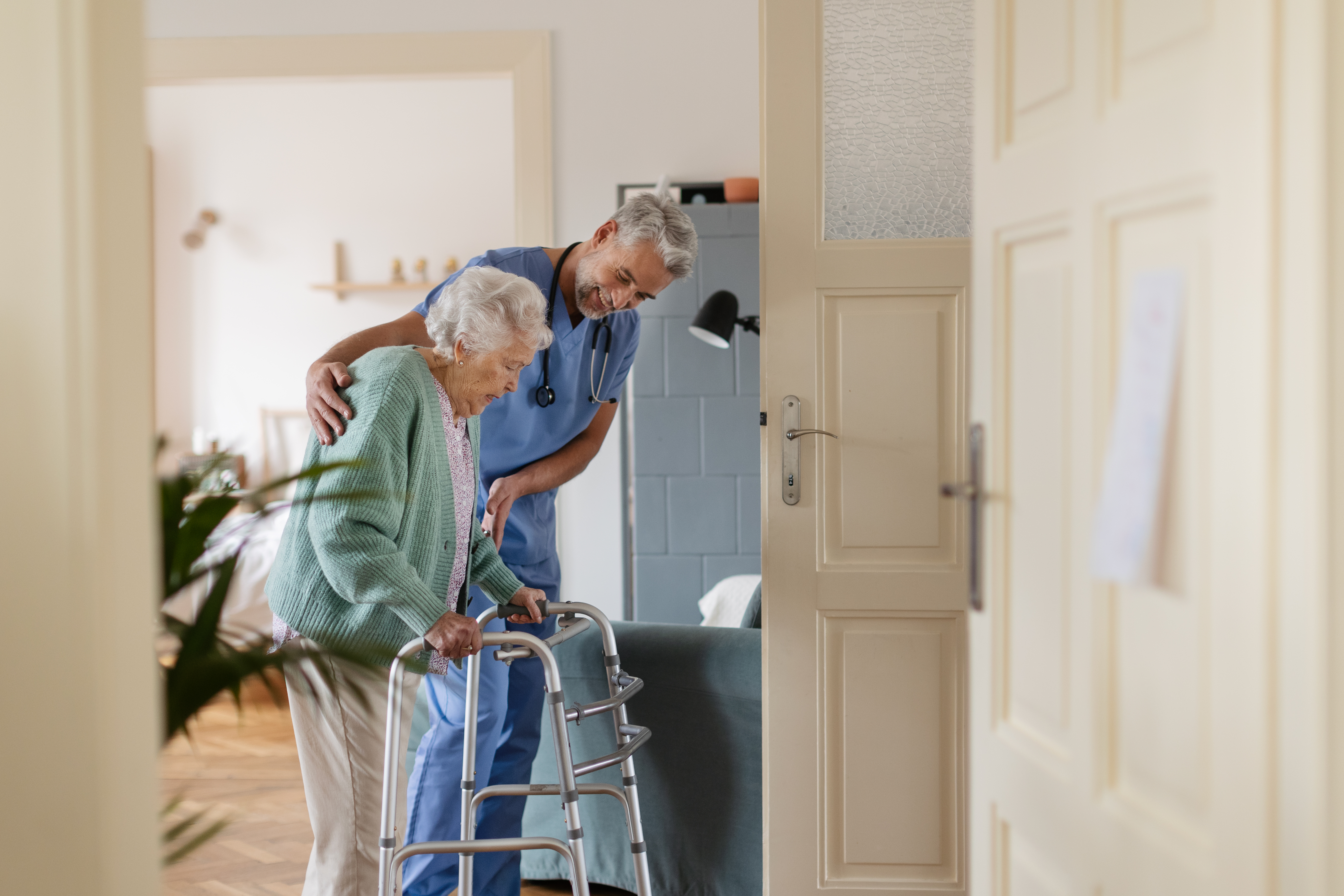 caregiver helping senior woman to walk in her home 77258502bf21b17165af