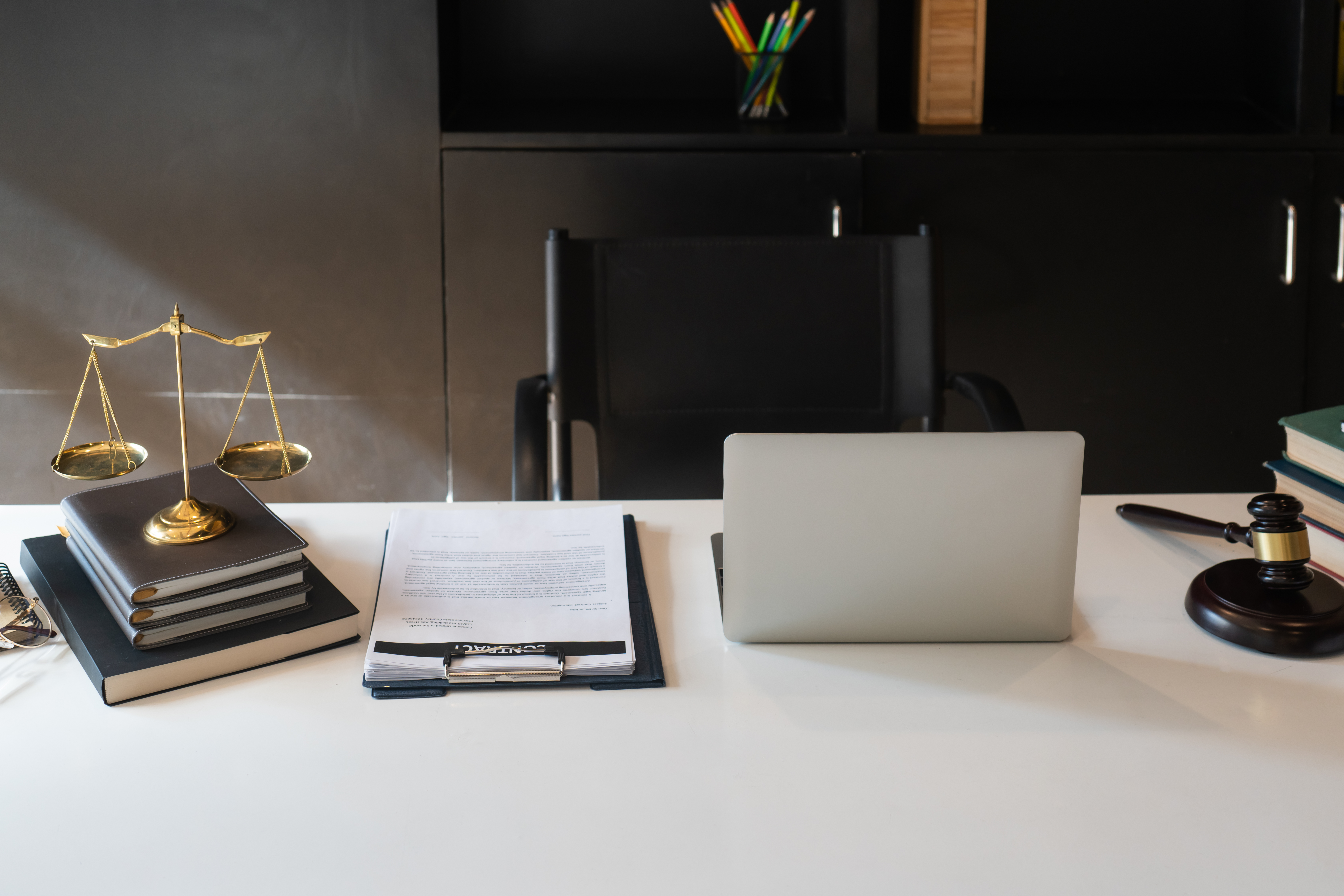 Desk with legal scales, stacked law books, legal documents, a laptop, and a gavel, symbolizing criminal defense and trial advocacy in Tidewater.