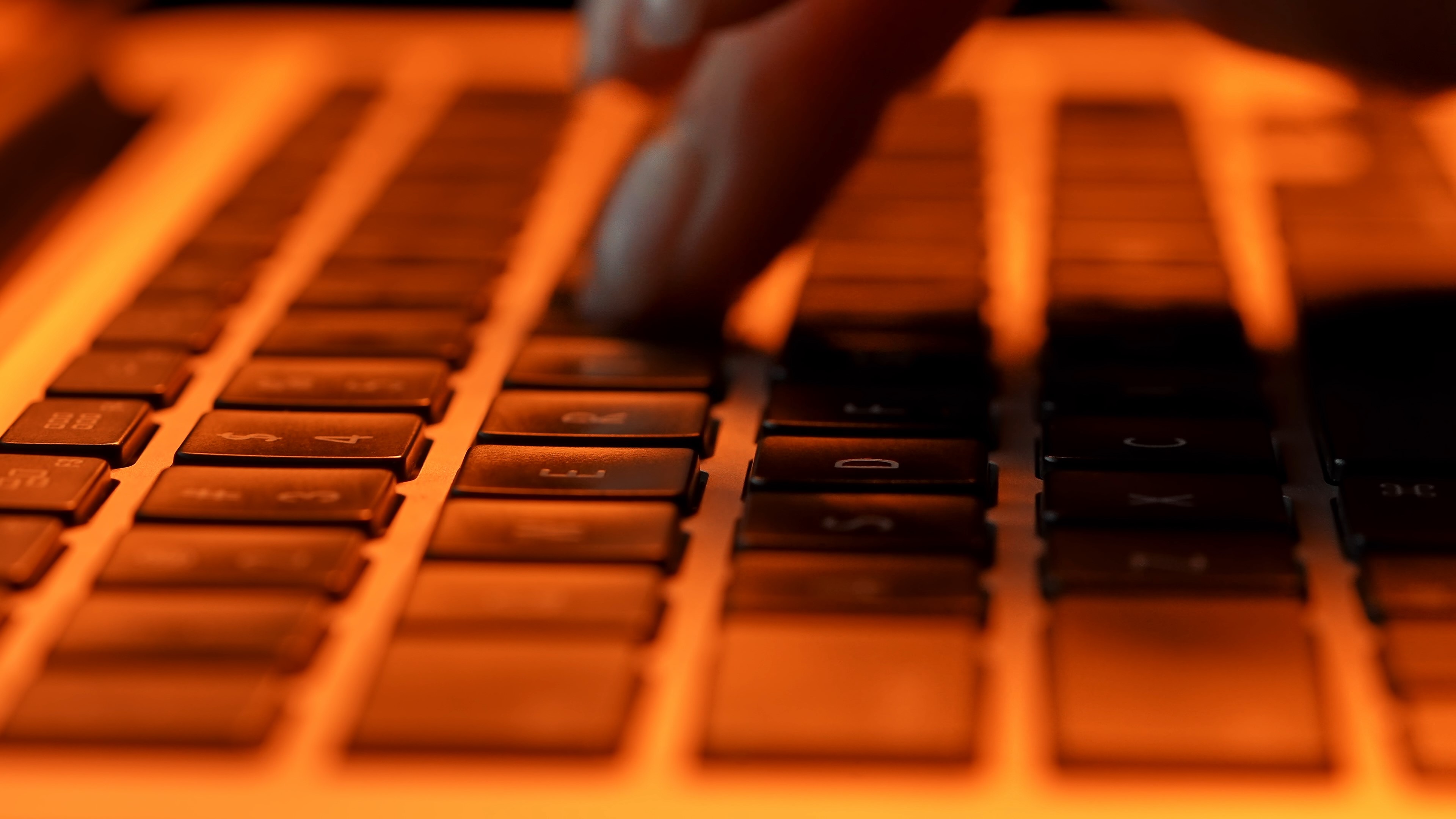 close up of hands typing on keyboard in dim lighti 65b49376054fed302c7f