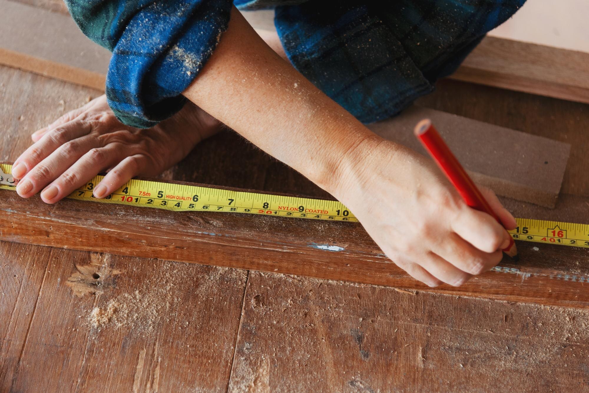Closeup of hands measuring wood with a tape measur de5cc4b96ef1498e639e