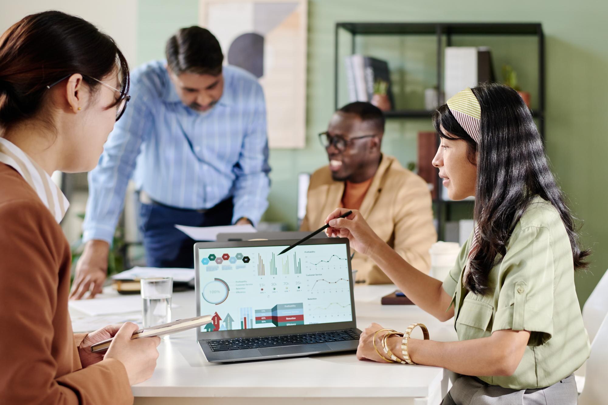 Diverse team collaborating in modern office, analysing data on laptop screen, discussing local SEO strategies and Google Business Profile optimisation.