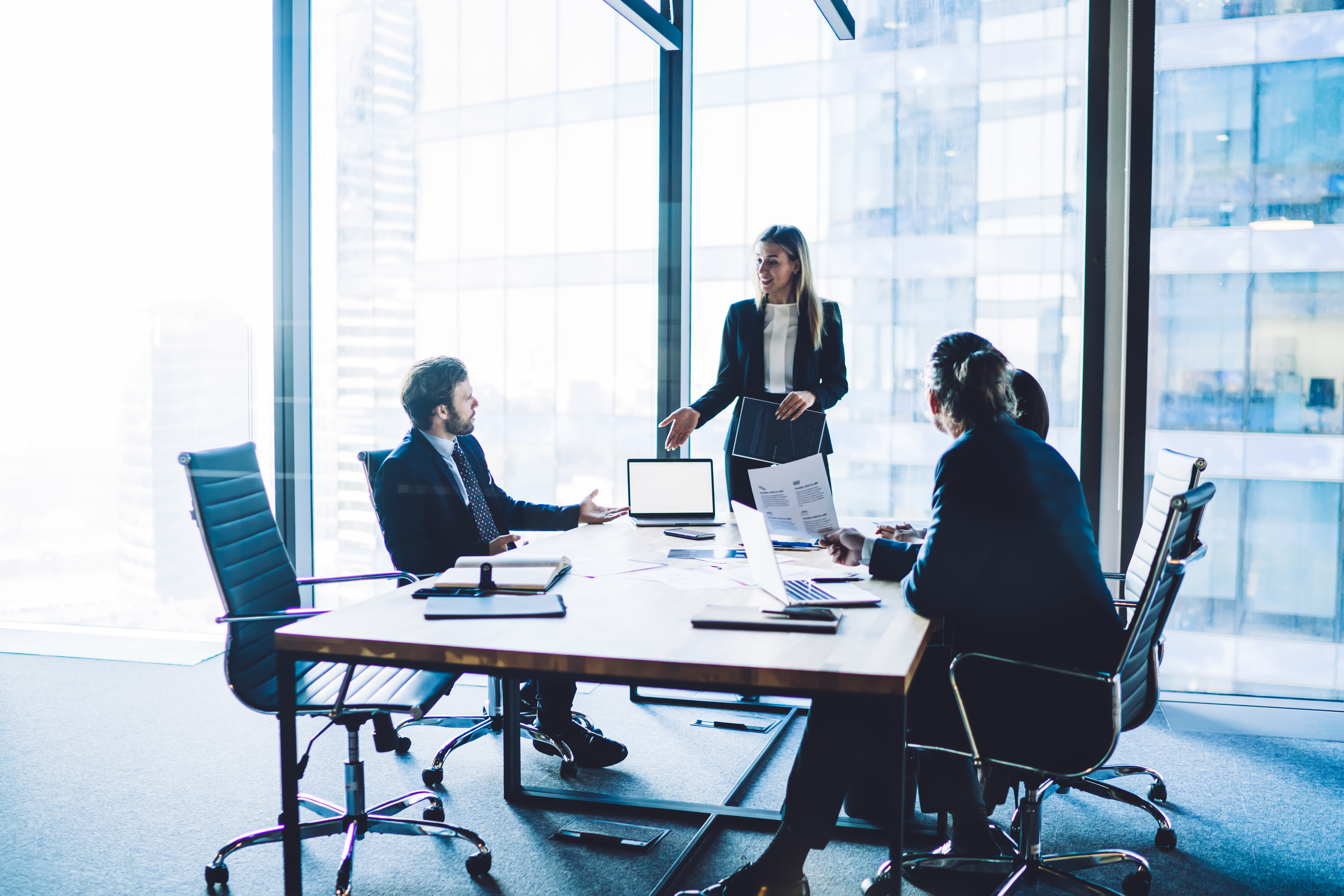Business meeting in a modern office, confident female director presenting ideas to male colleagues, emphasizing legal strategies and intellectual property protection.