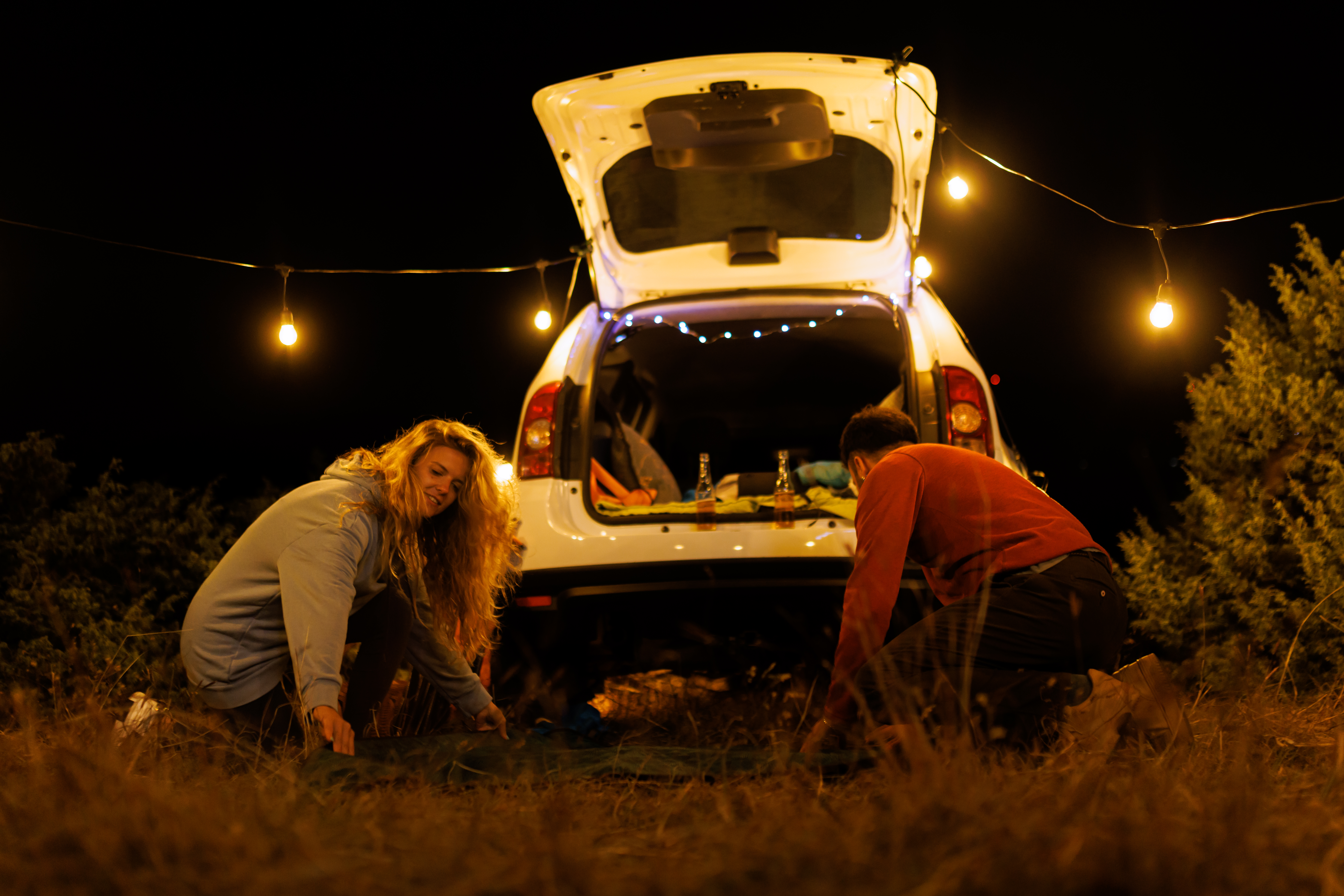 couple setting up a cozy night under string lights 9804eb3a726ee2ea1a0f