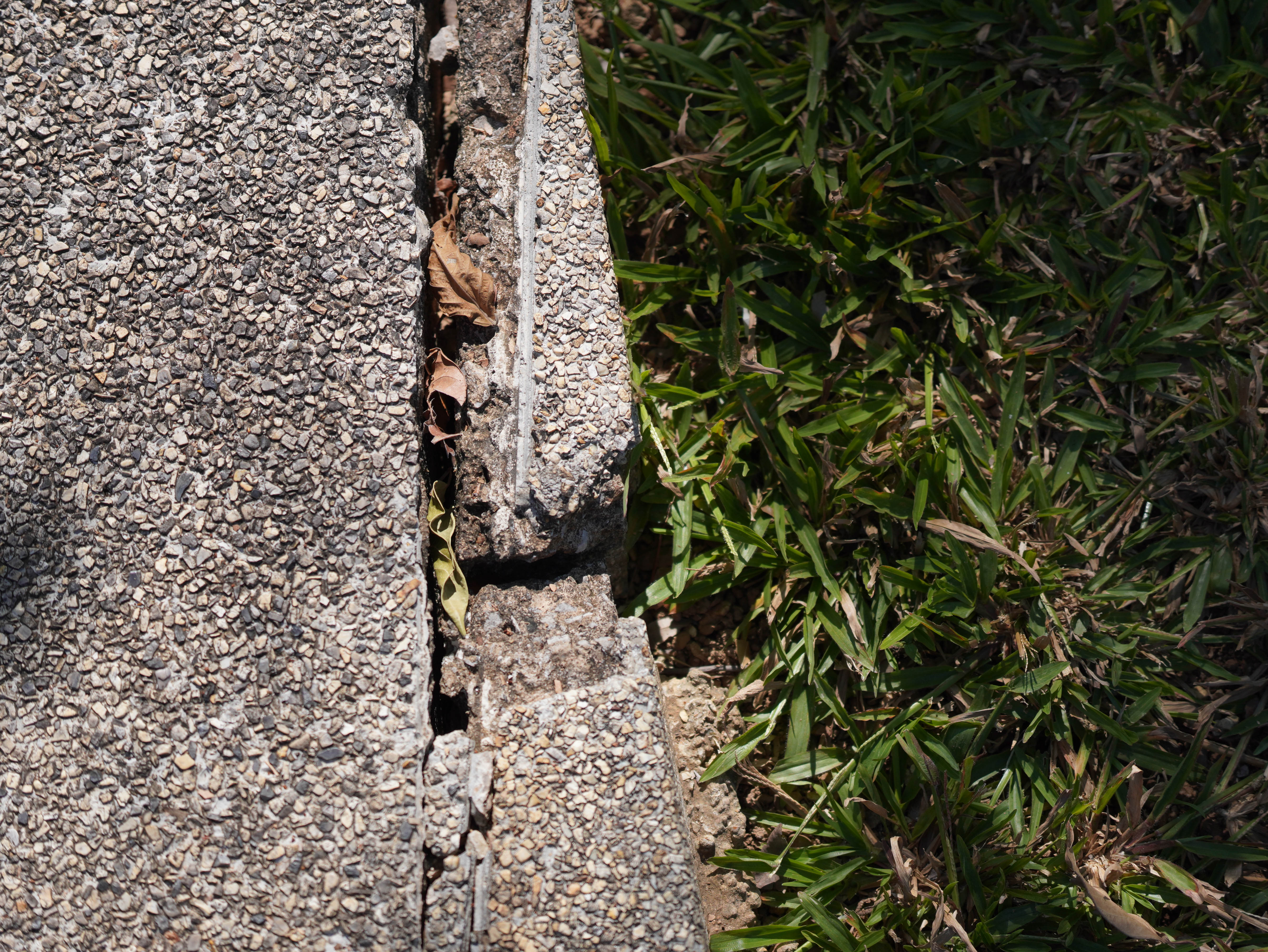 alt="exposed aggregate cracks and damages on concrete walkway"