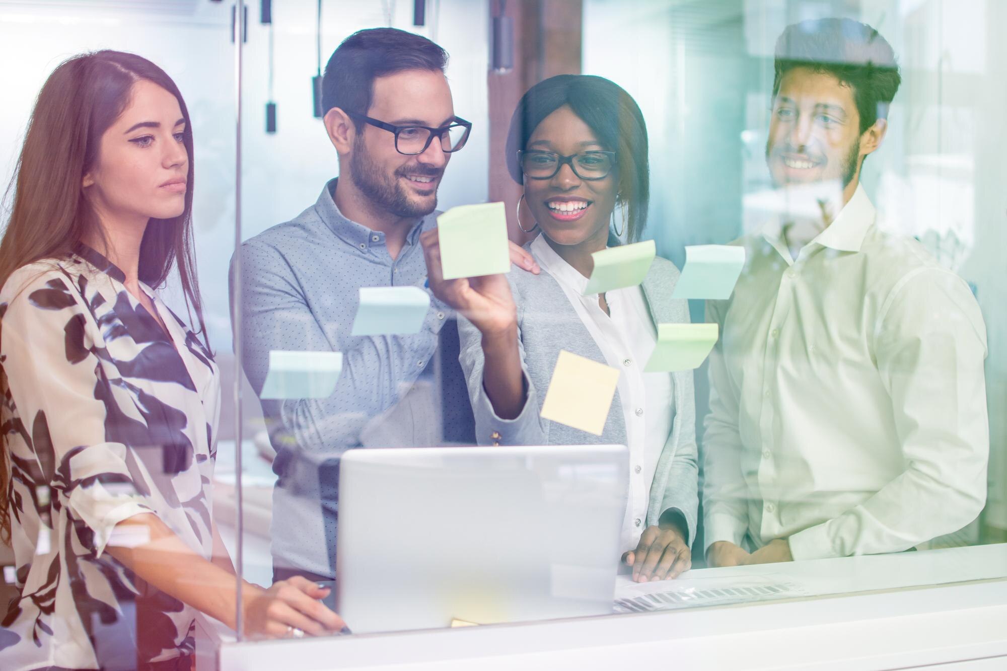 Business team collaborating and discussing ideas in front of a glass wall with sticky notes, illustrating automated Google Business Profile updates and local SEO strategies.