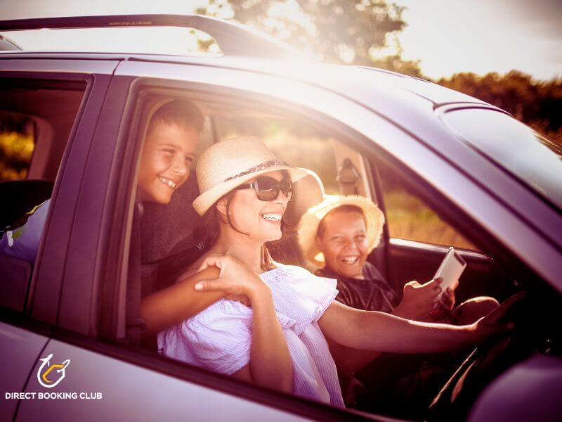 Smiling Texas family sitting in a car, ready to start a road trip vacation with the Direct Booking Club logo in the corner.
