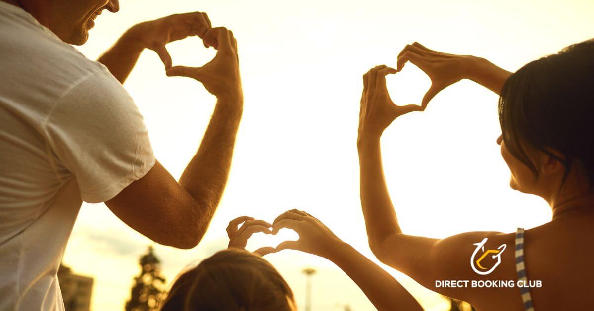 Family making heart shapes with their hands at sunset during a Texas vacation, with Direct Booking Club logo in the corner.