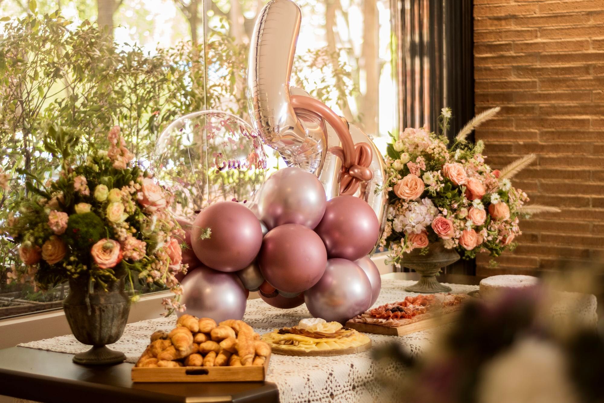 Decoración con globos y numerales en tonos rosados para celebración