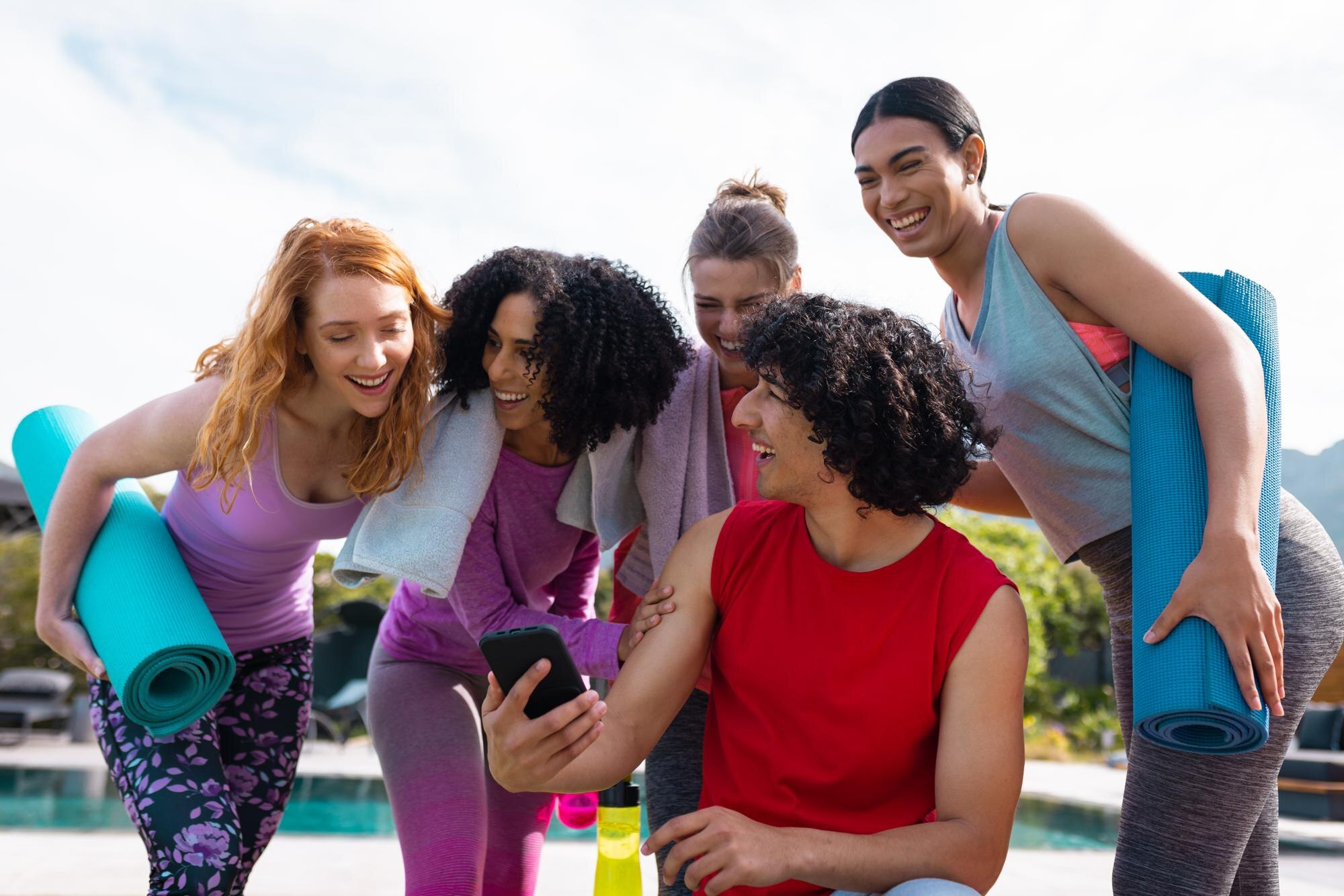 Cut Through The Noise: Real Tips For Everyday Wellbeing 4 Diverse Friends Using Smartphone And Holding Yoga F3A02D8Ee910E9Eae860