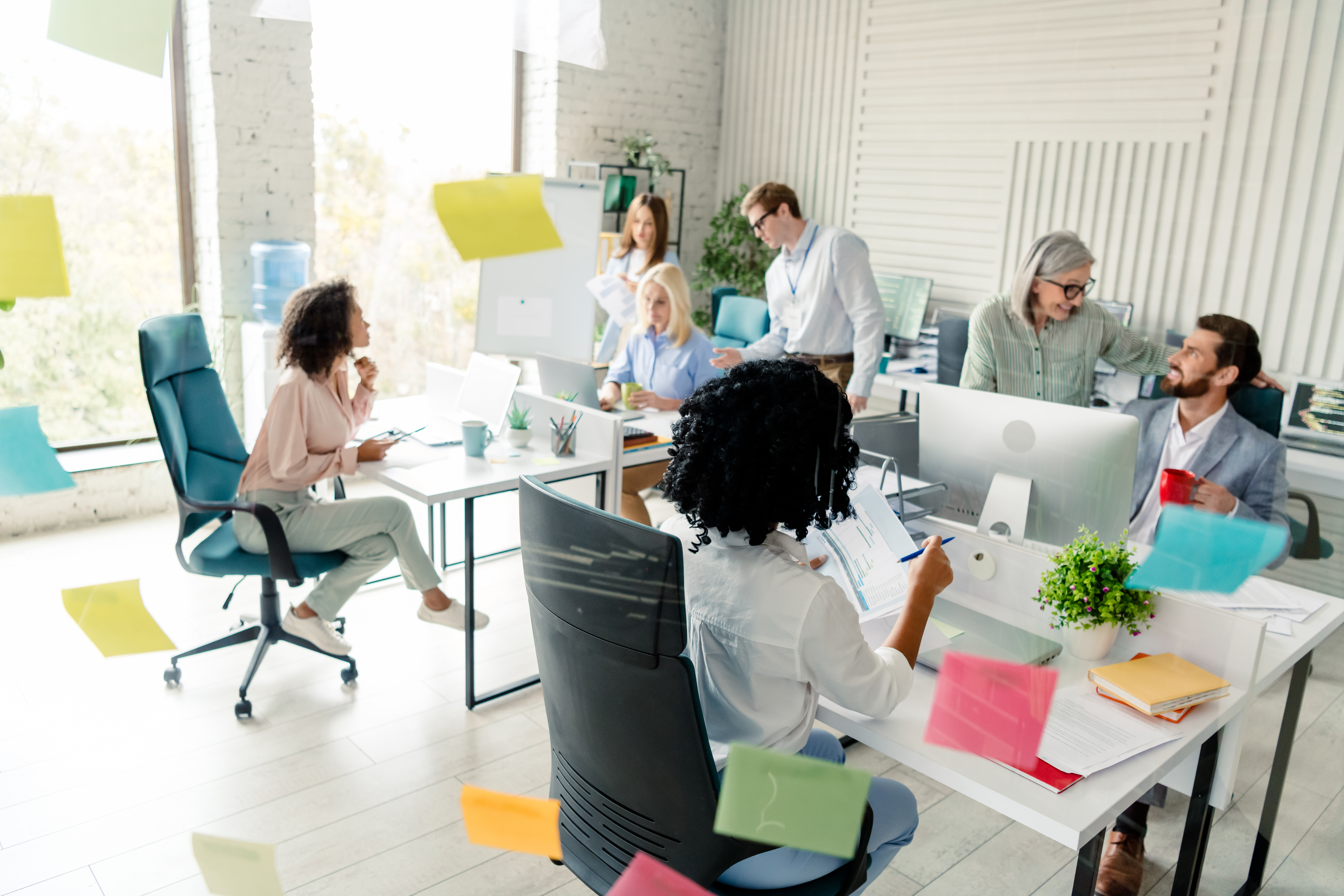 an open work space filled with desks and coworkers sitting at computers in a well lit office