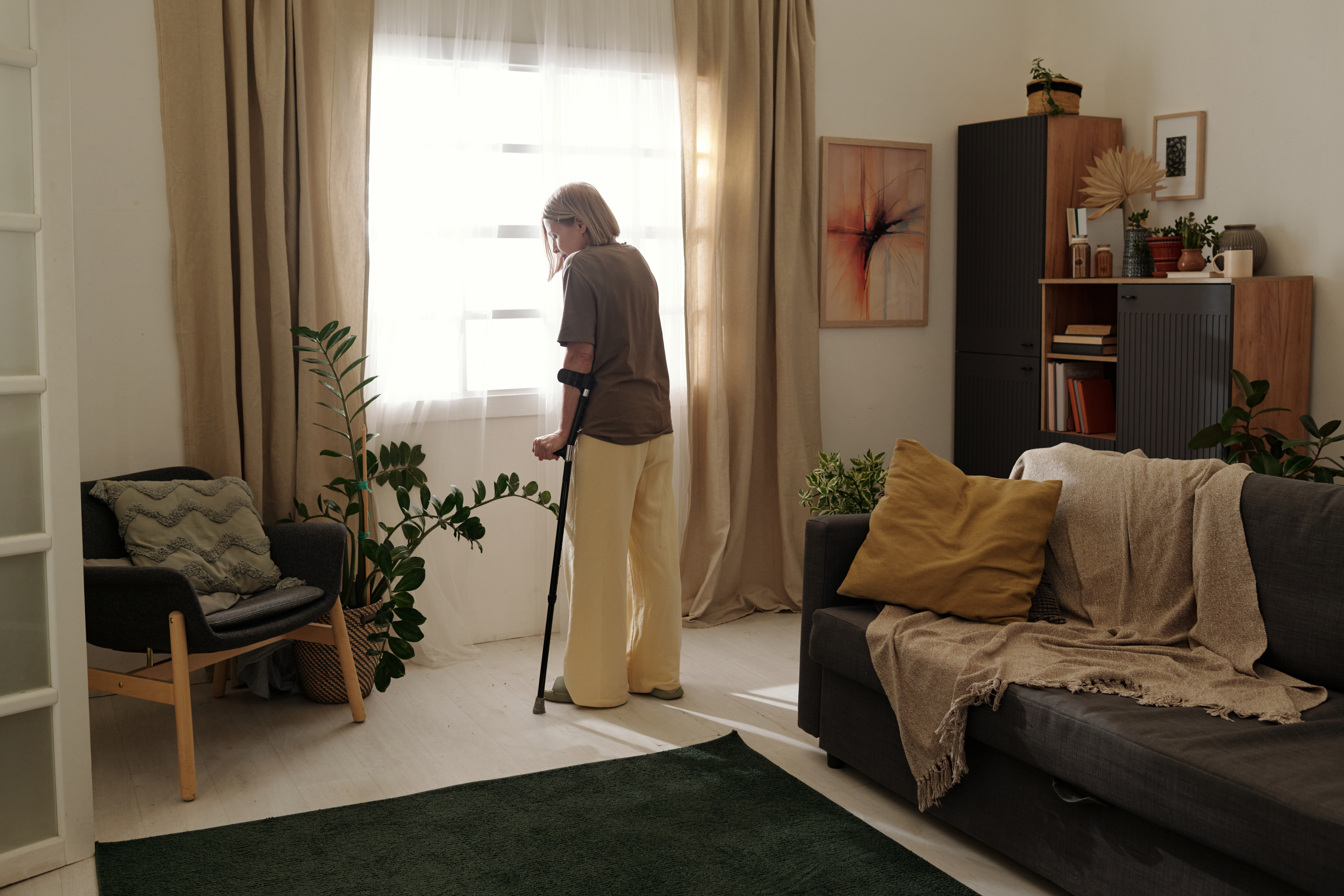 elderly woman standing near window holding walking fe3f4012d07d6b8ceeee