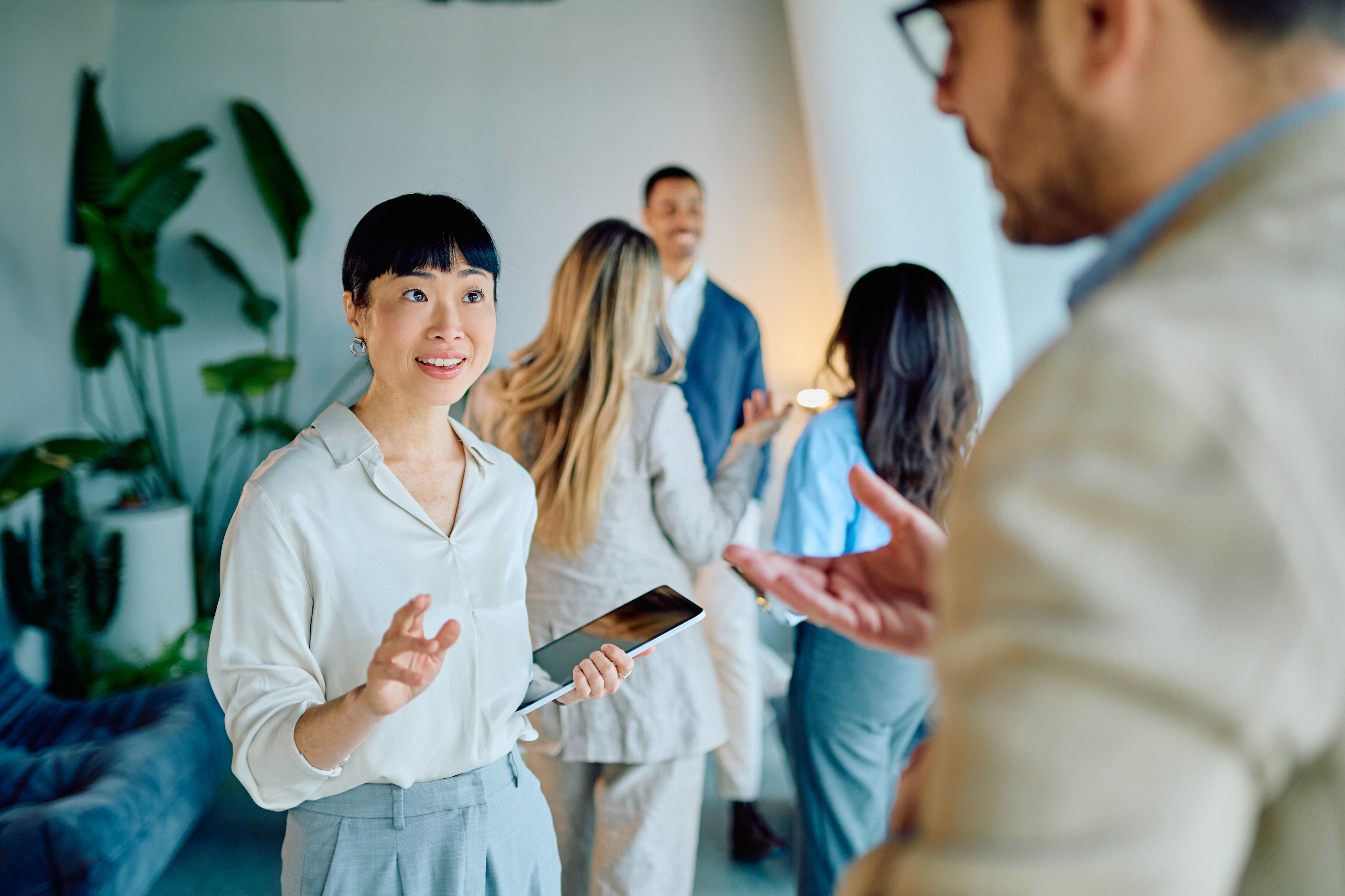 Multicultural business team collaborating in a modern office, woman engaging with colleagues, discussing video content strategies to enhance Google Business Profiles and attract local customers.