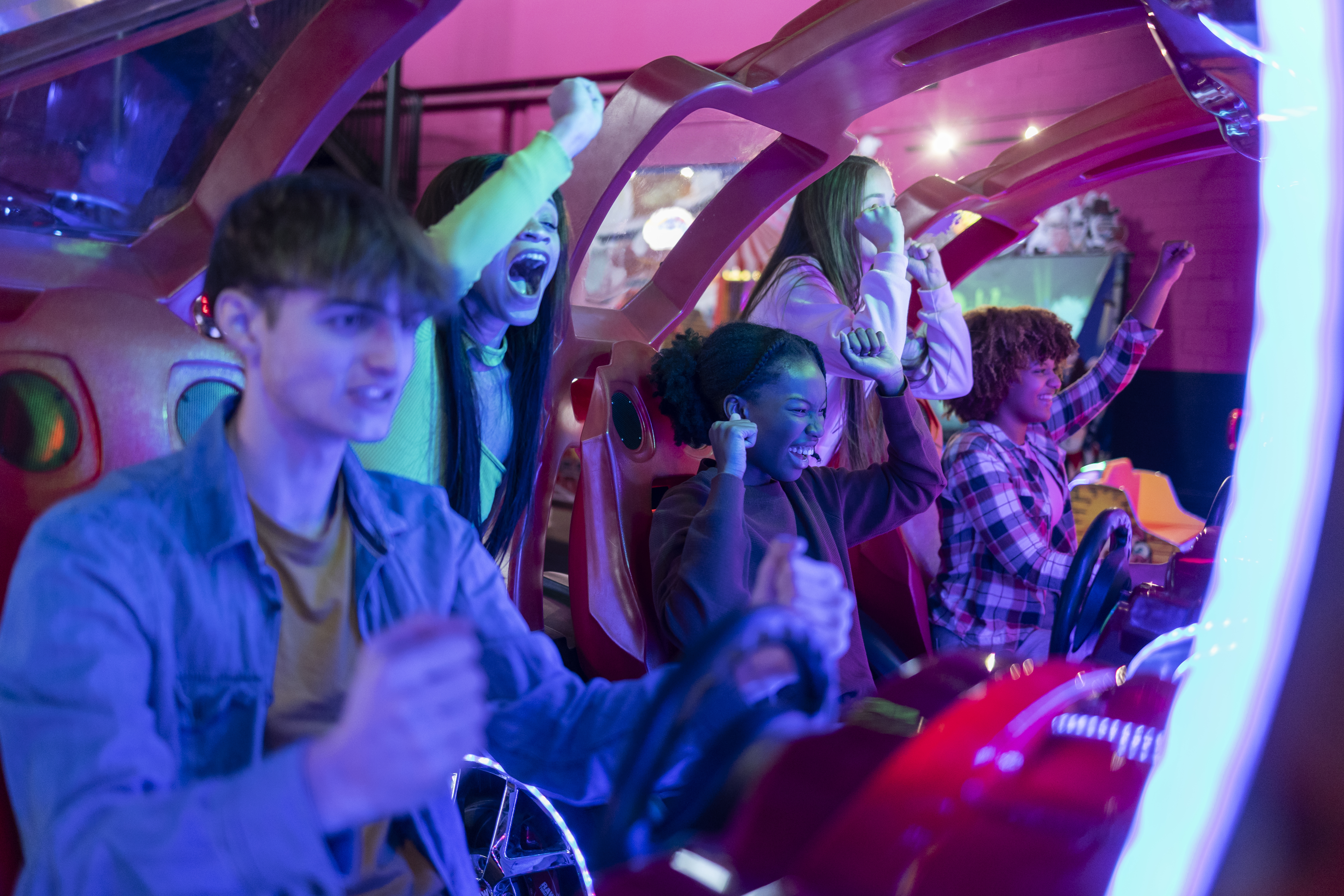 excited friends playing arcade racing game togethe 3e4d357f68ae425d4560