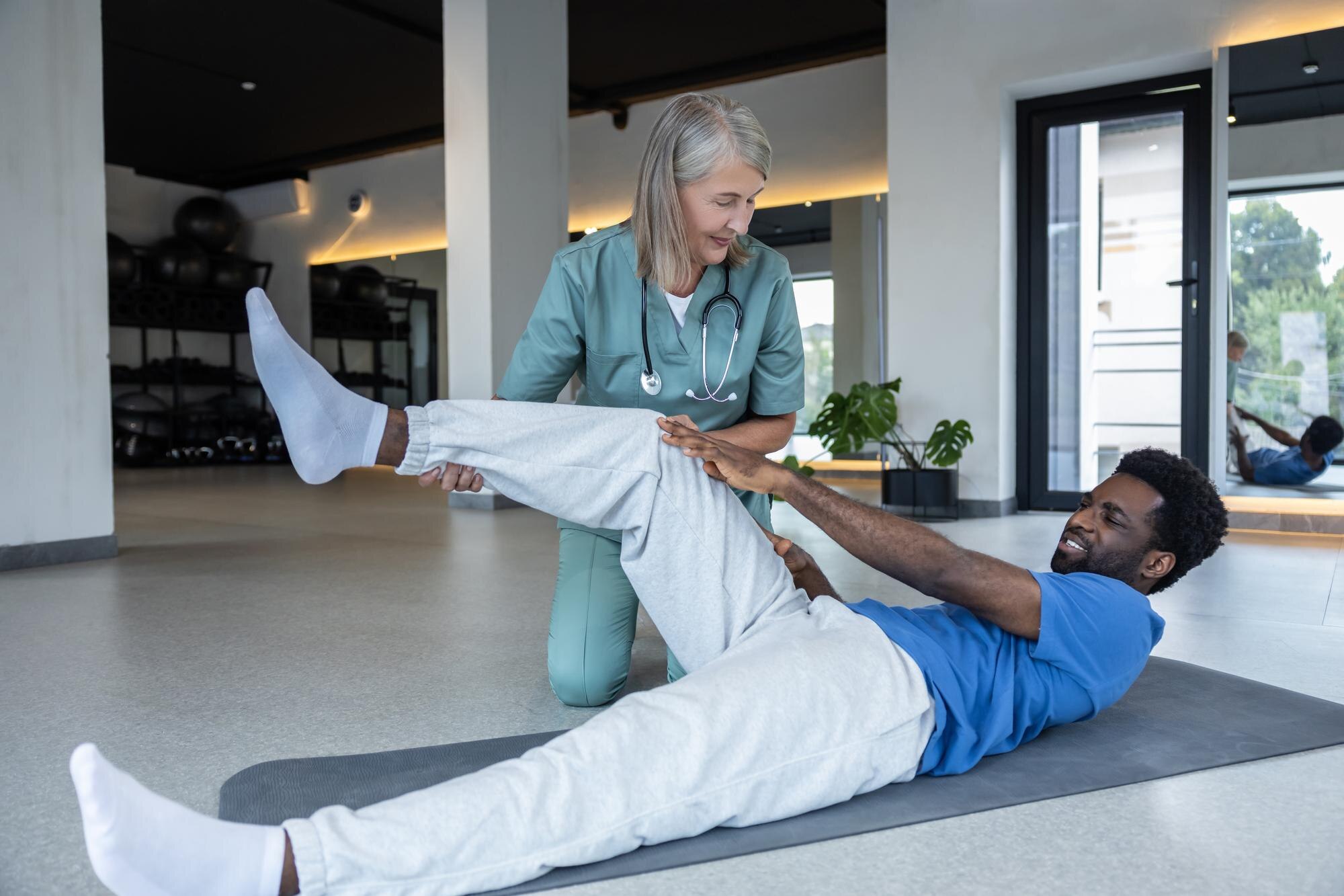 female physical therapist helping her male patient 3796346b52f43aead6cd