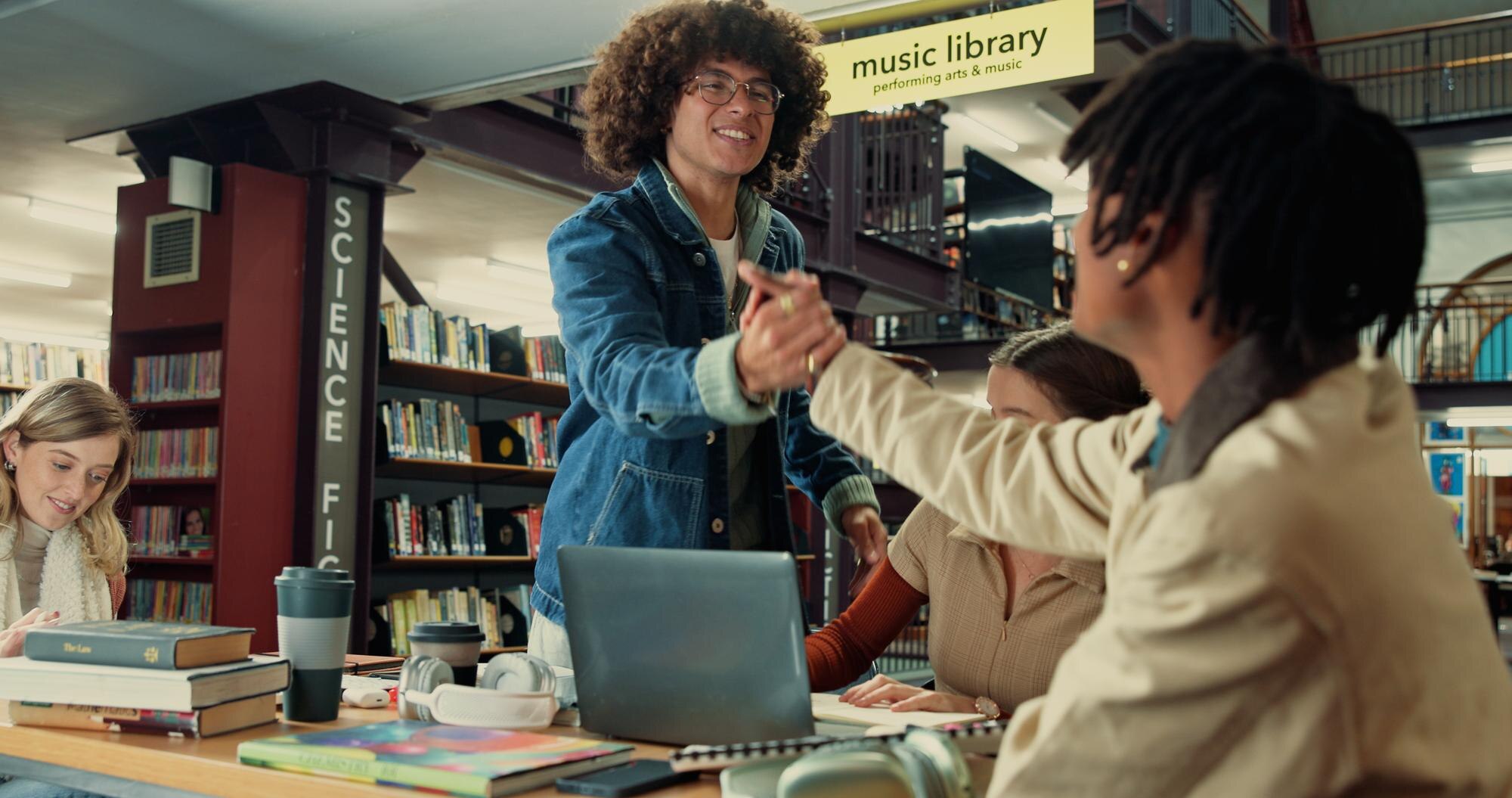 group handshake and college with friends in librar 564b38ff01bfcbae3c3c