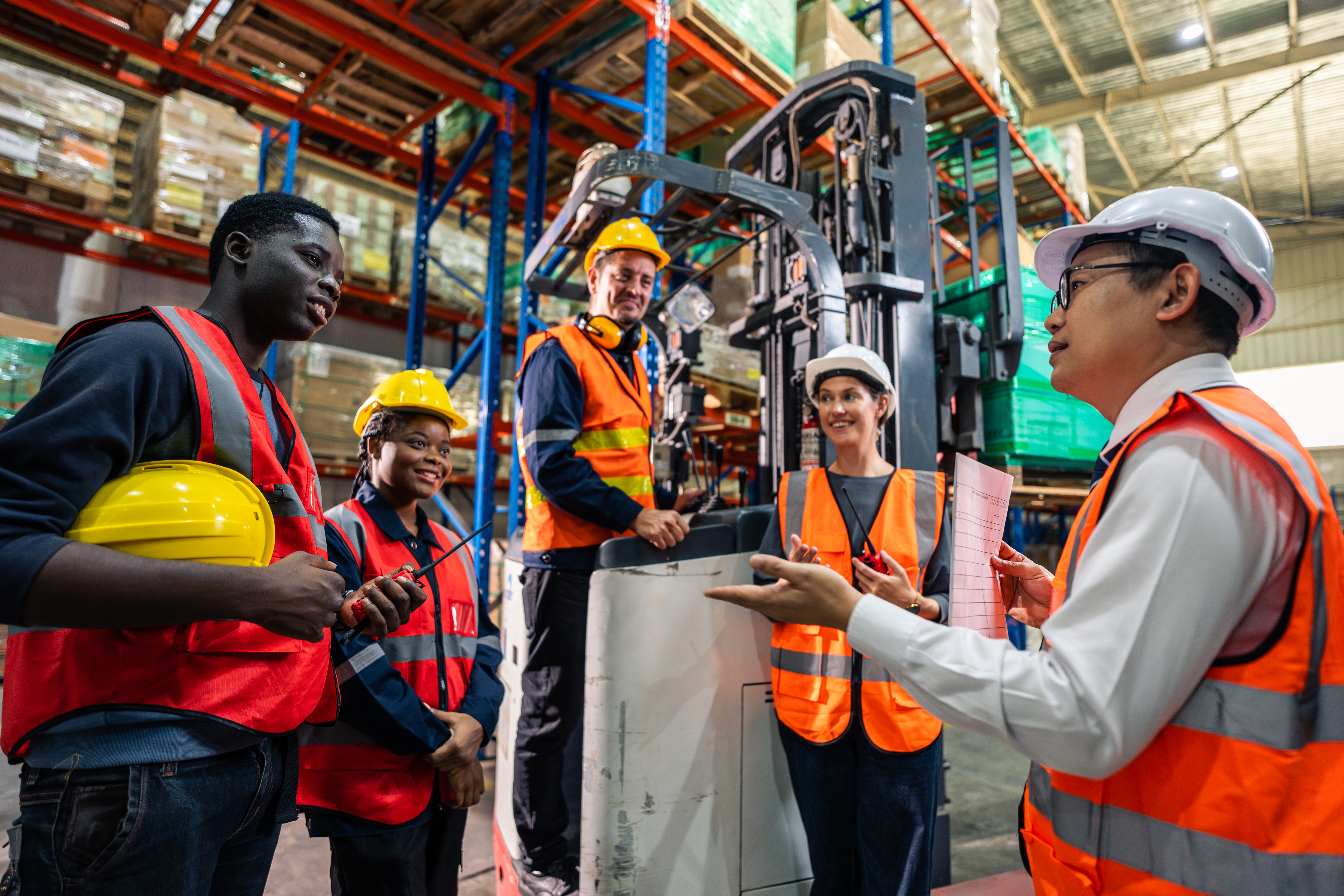 Een groep magazijnmedewerkers volgt een veiligheidstraining met uitleg over heftruckgebruik