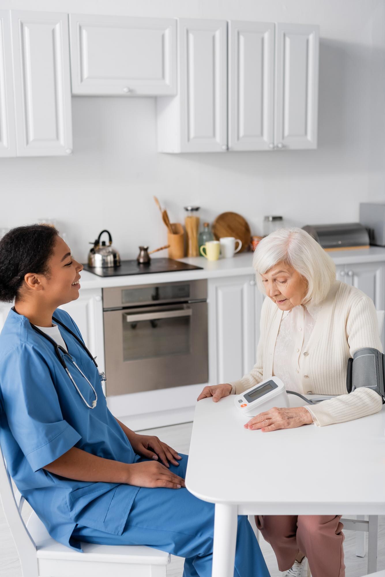 happy multiracial nurse looking at senior woman wi 0a739b8788e3c0d8eef5