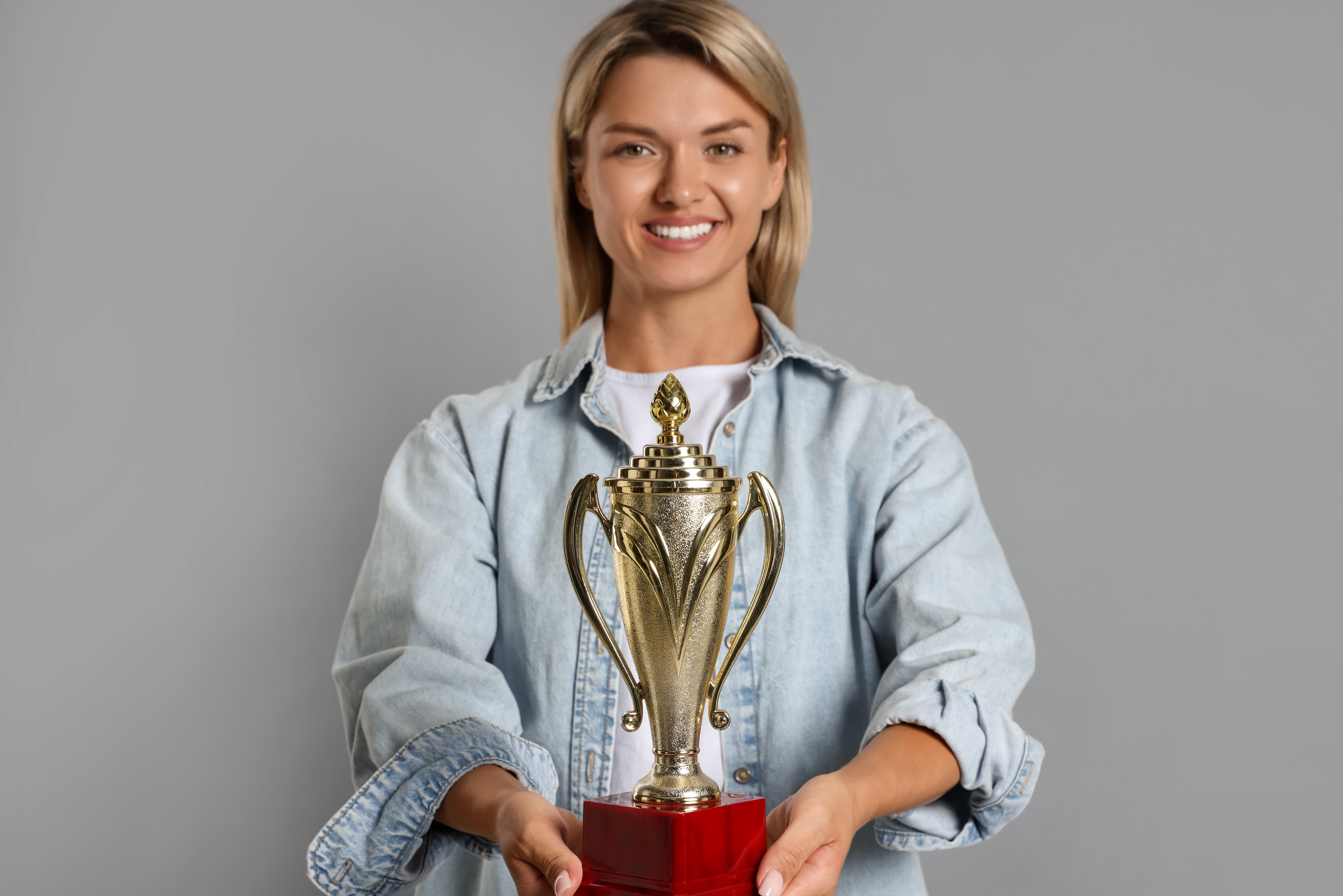 Why Business Excellence Awards Matter When Choosing a Plastic Supplier 3 happy winner with golden trophy cup on gray backgr 9489f249901fb777e5b4