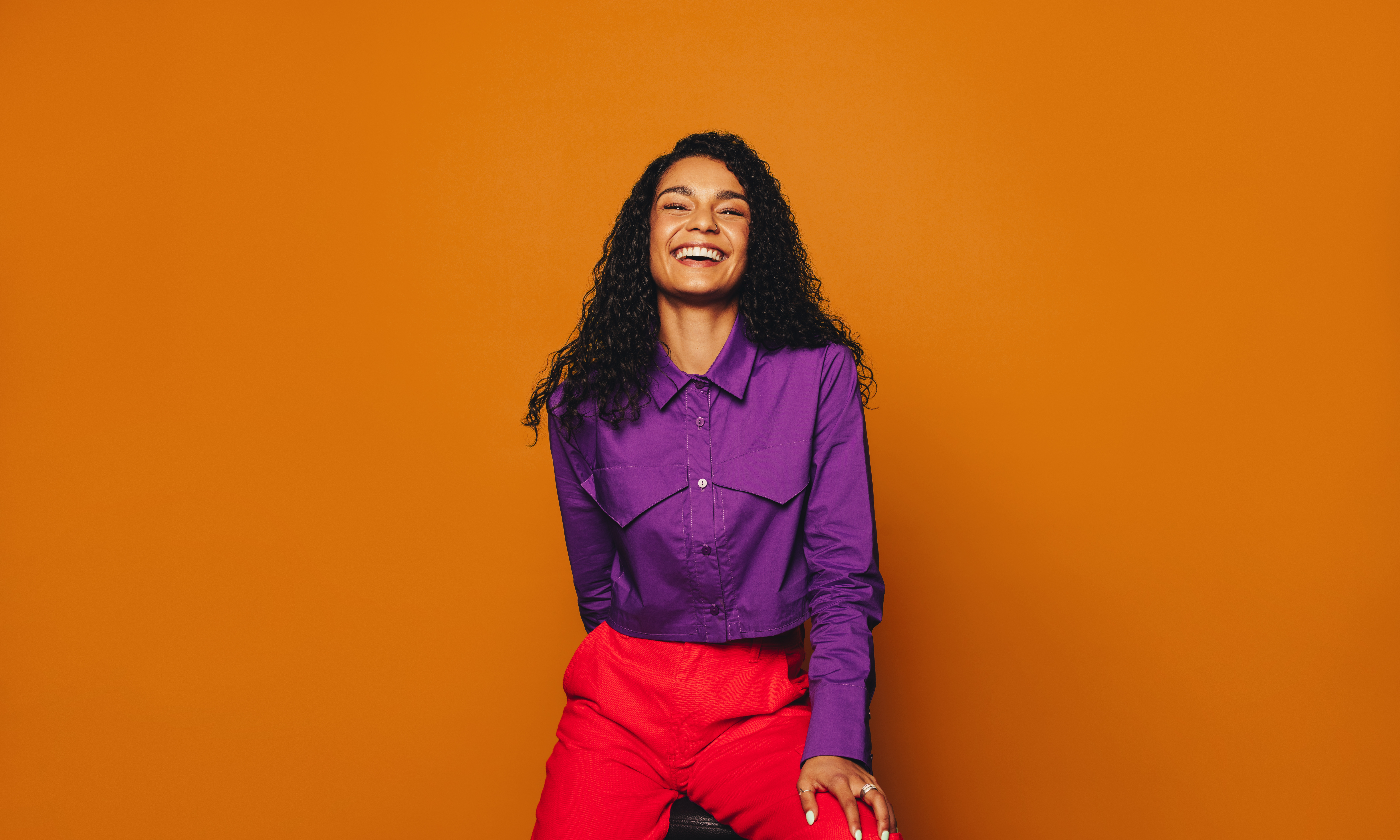 Featured image: Happy woman with curly hair on orange background-bf98227d2837c04c9bf4