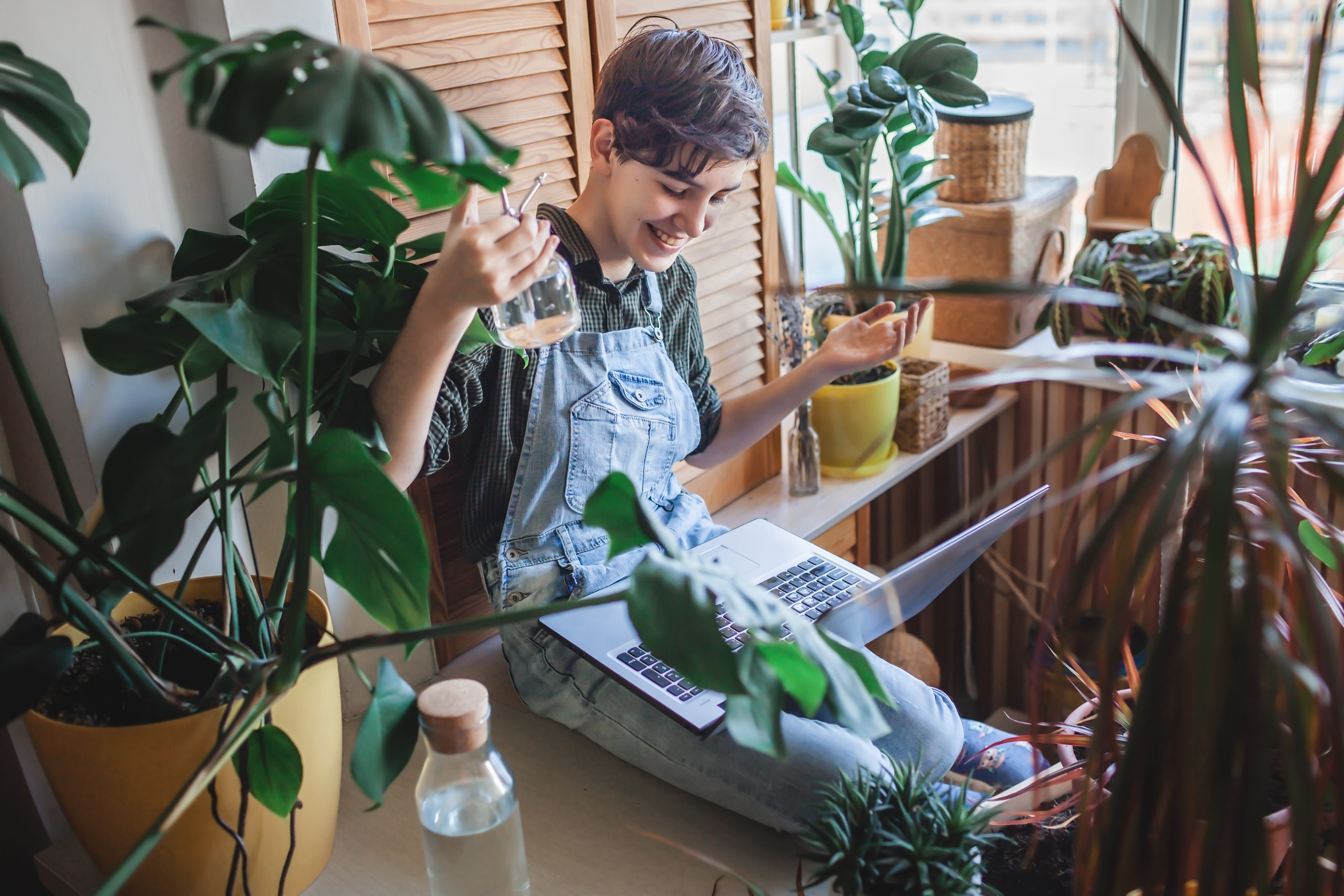 happy young girl with laptop among plants on balco 61798c30d33d2414eae1