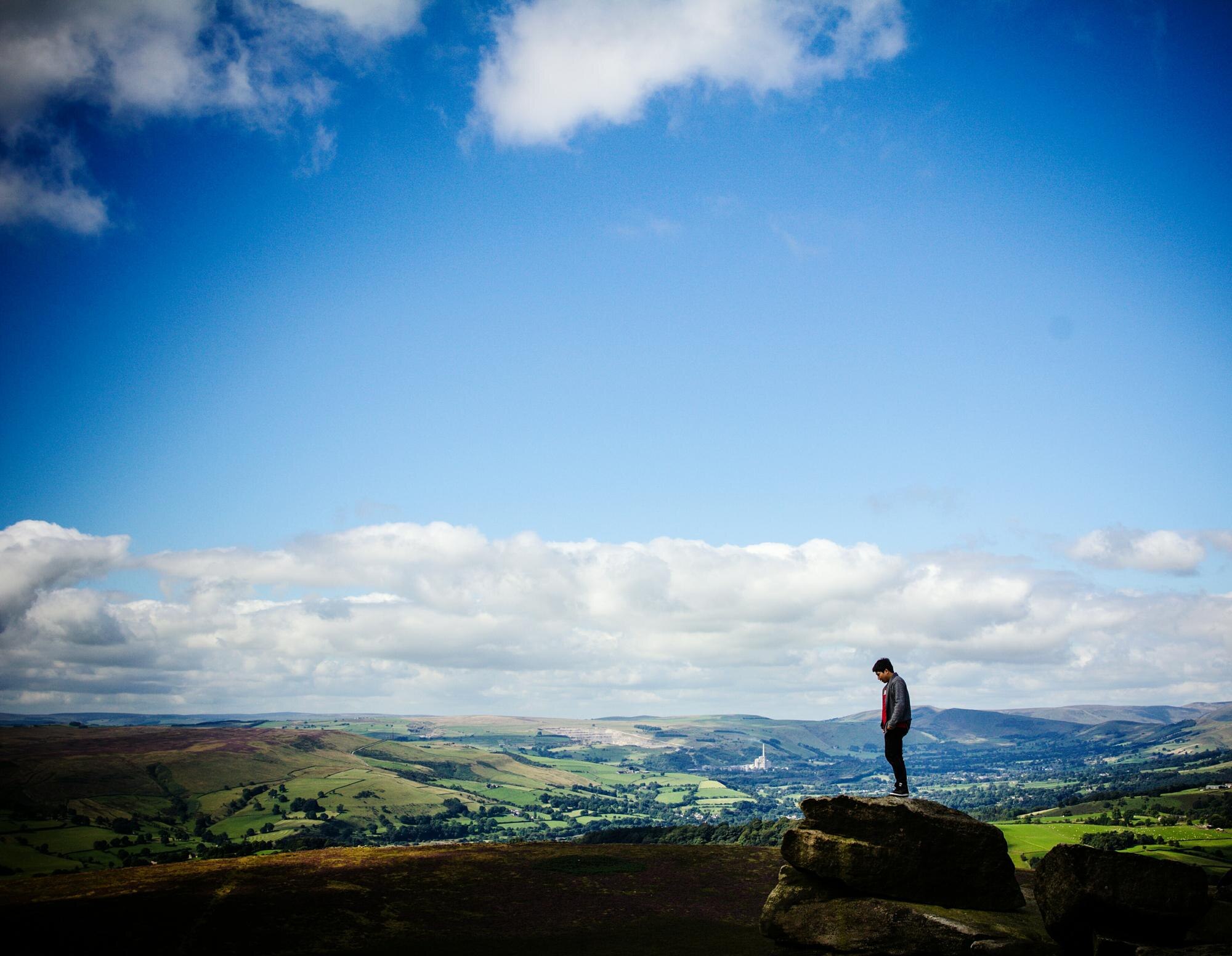 hiker standing on rock against sky cefc45b82f7f92a2f62e