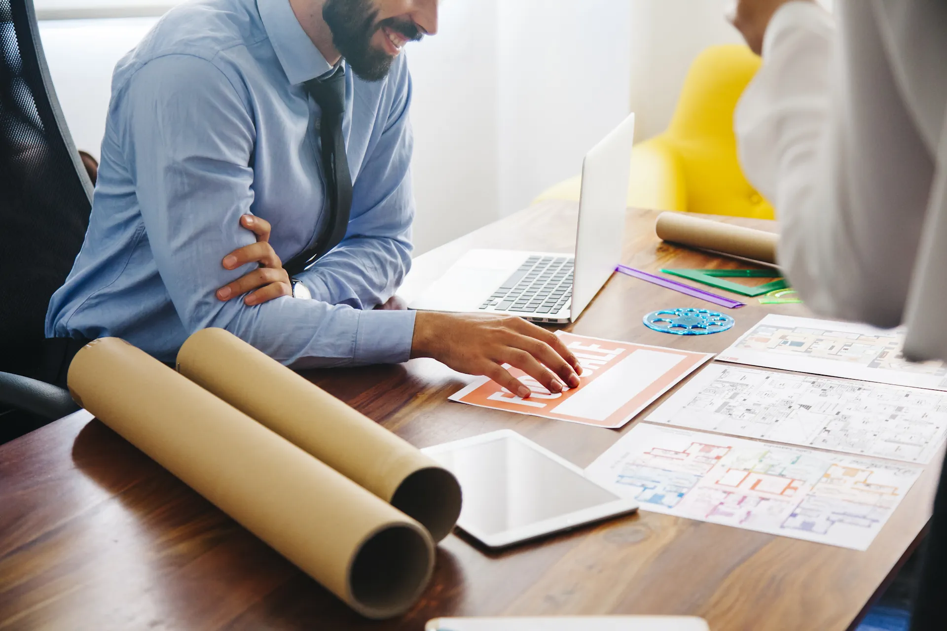 Business professionals collaborating over project plans and digital devices, emphasizing proactive IT management and monitoring strategies.