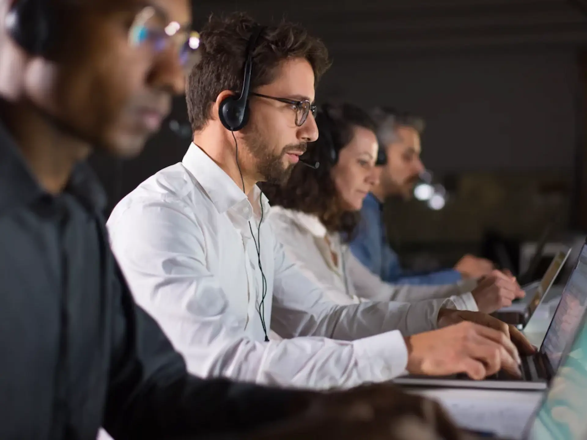 Team of IT support professionals wearing headsets, working on laptops in a dark environment, emphasizing local support and cybersecurity services for businesses in Australia.