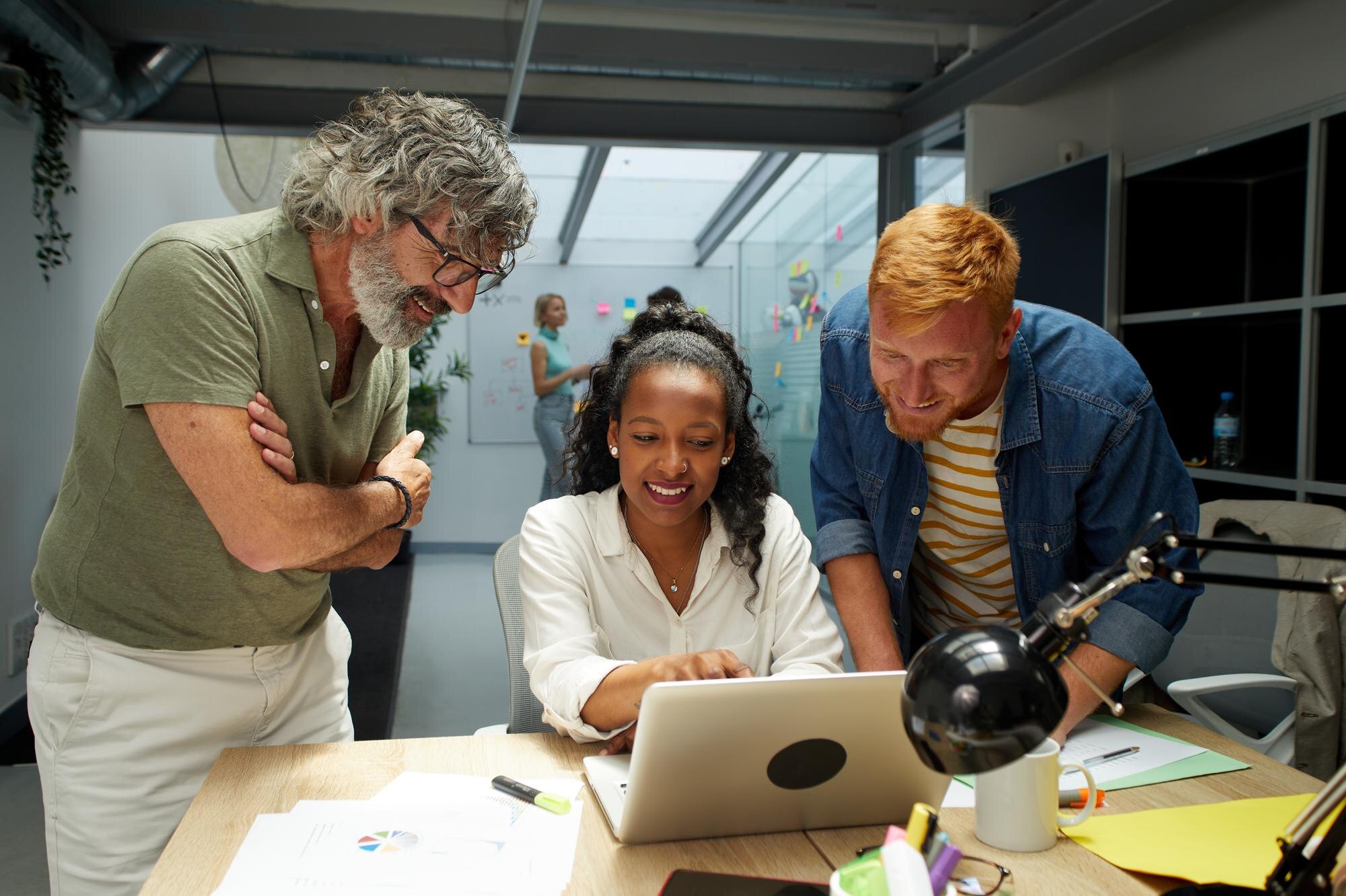 three people centered around a computer collaborating