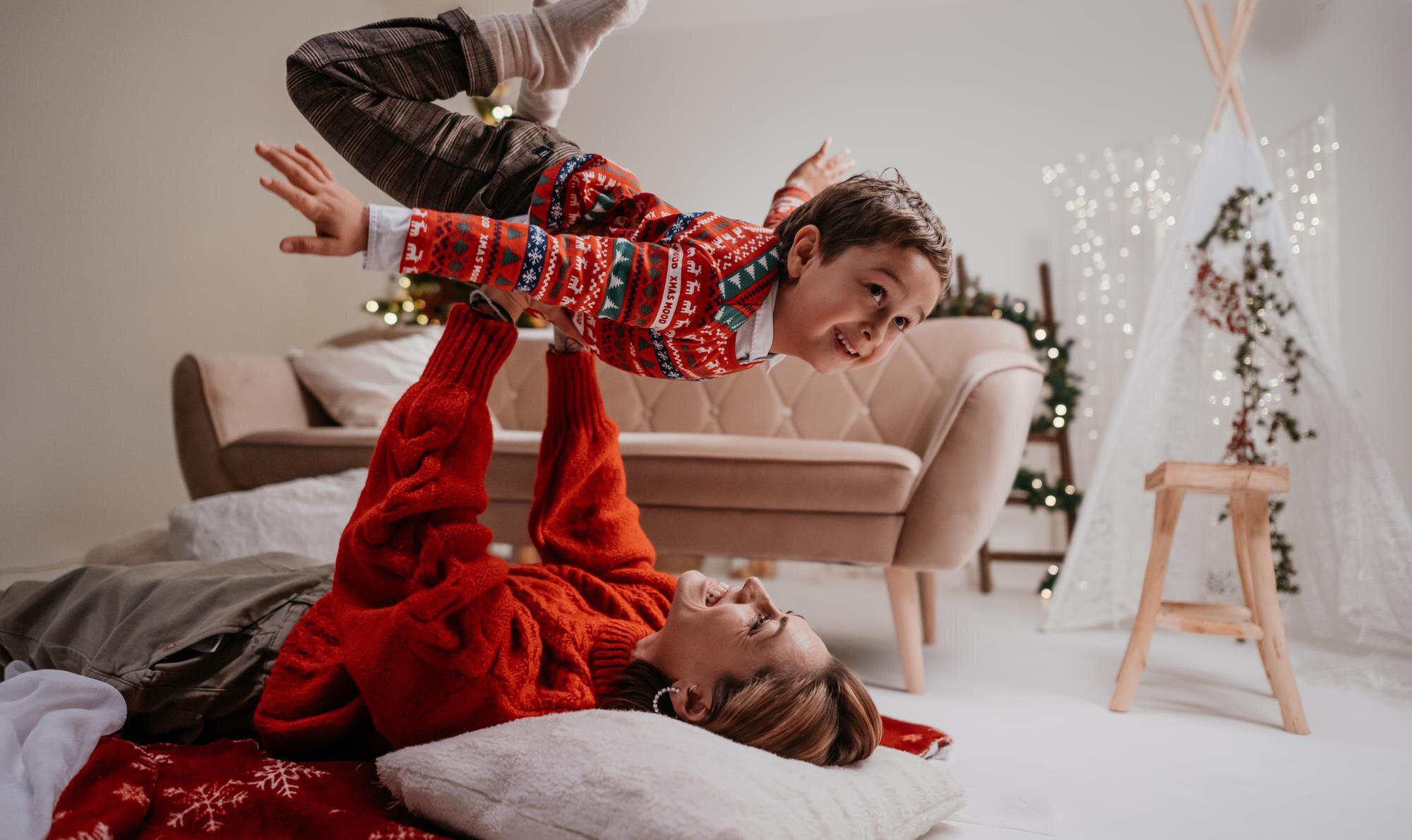 joyful young playful mother lying on bed and holdi 54cf8534ce43c40d356c