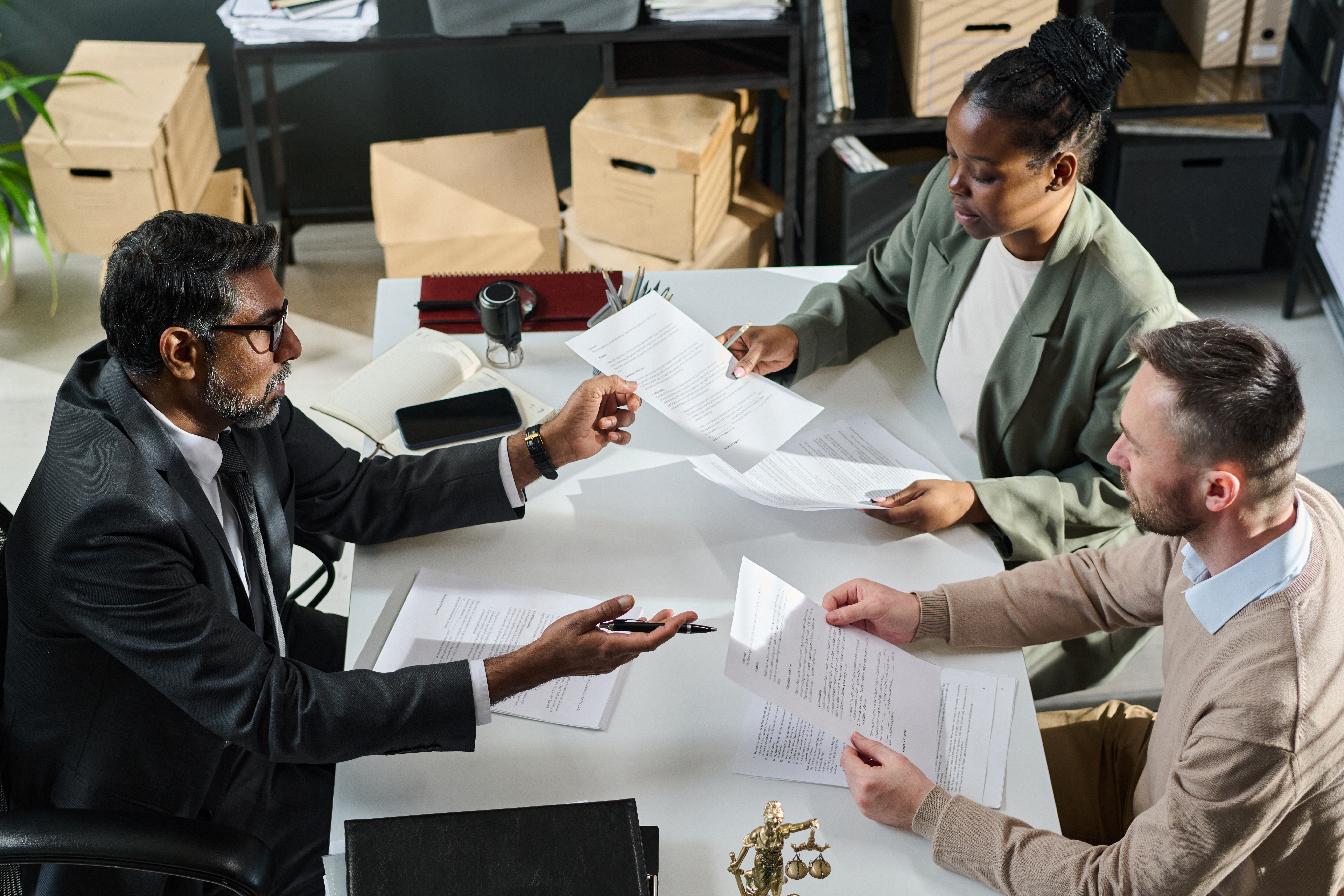 Business professionals discussing documents during a legal consultation, emphasizing compliance and risk management for small business owners.