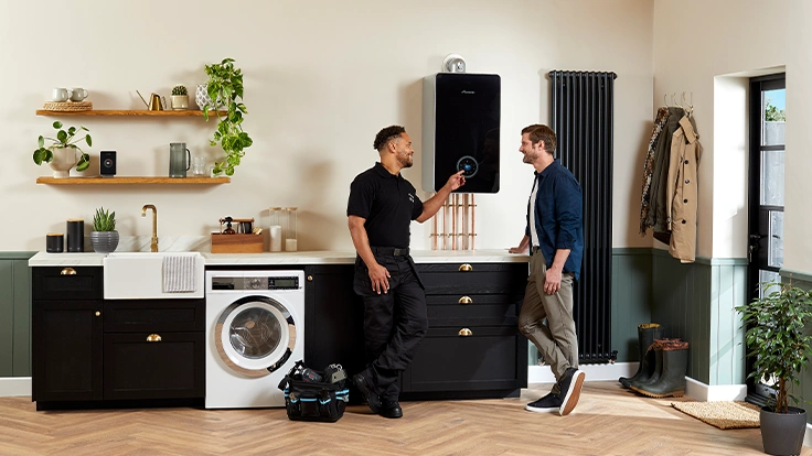 Heating engineer explaining a boiler installation to a homeowner in their kitchen