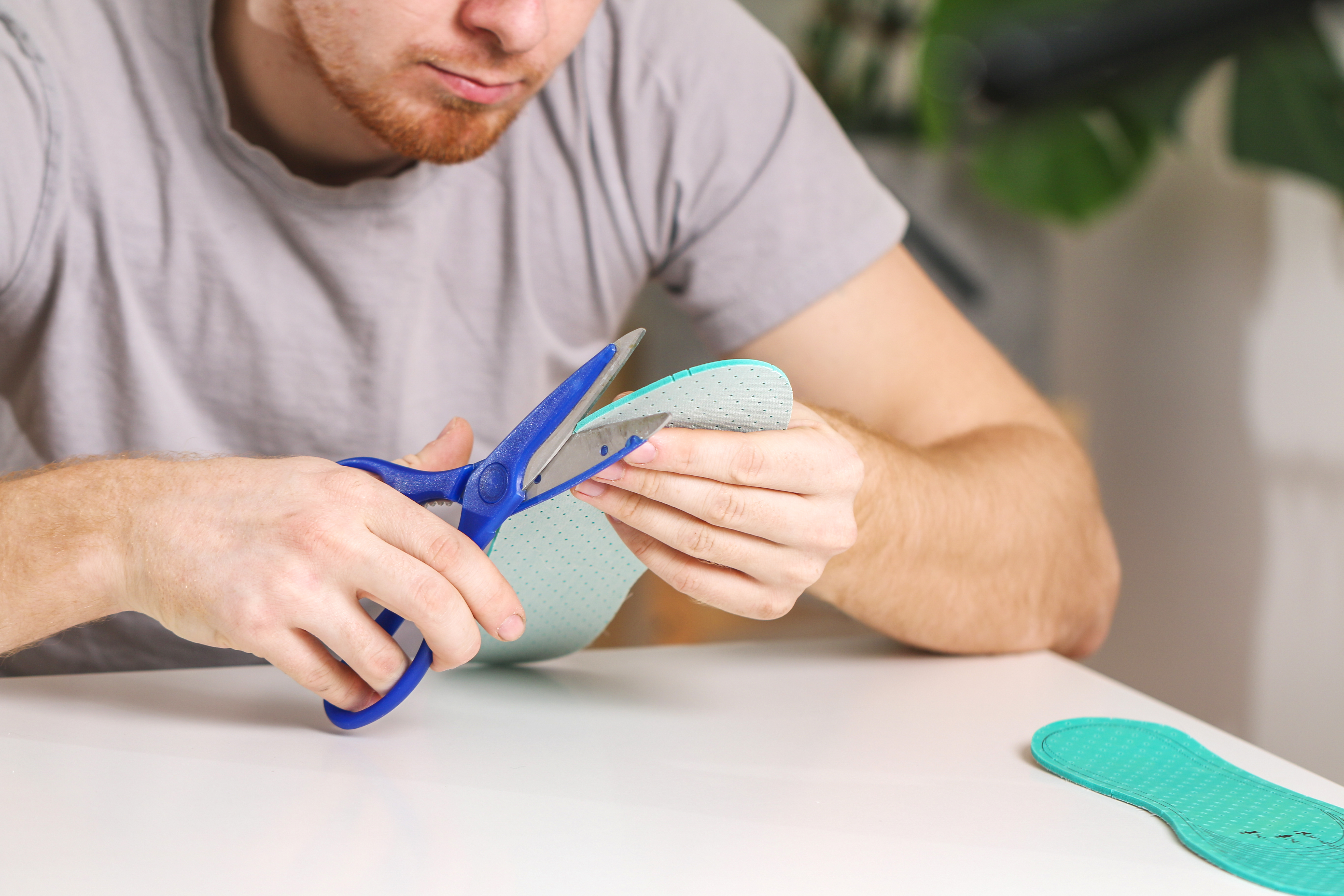 Top challenges in plastic cutting and fabrication — and expert tips to avoid them 1 man cuts out new shoe insoles with scissors to fit 191e2baf897c07d0a98f
