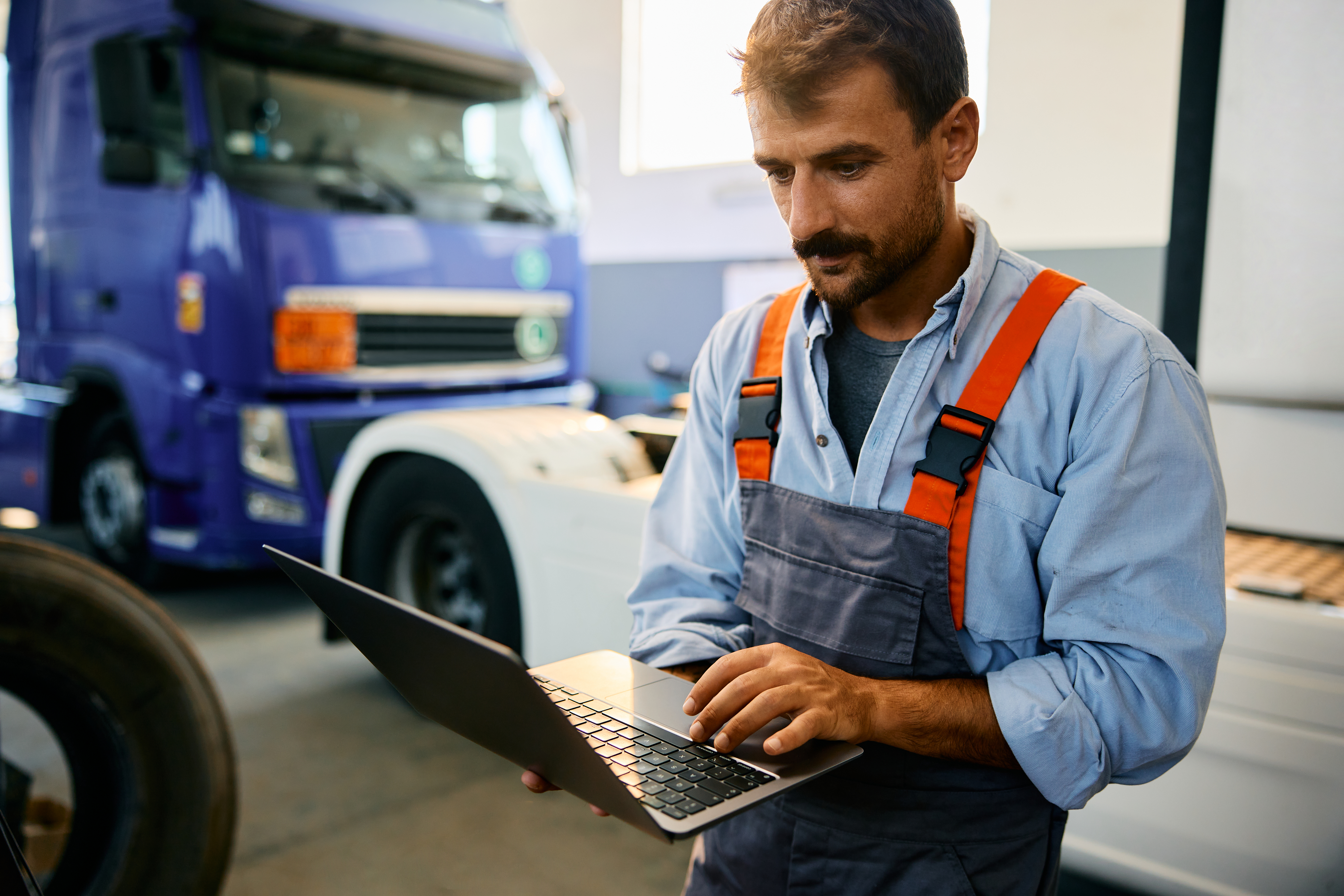 mechanic using laptop while working at truck repai f137869100173e665b74