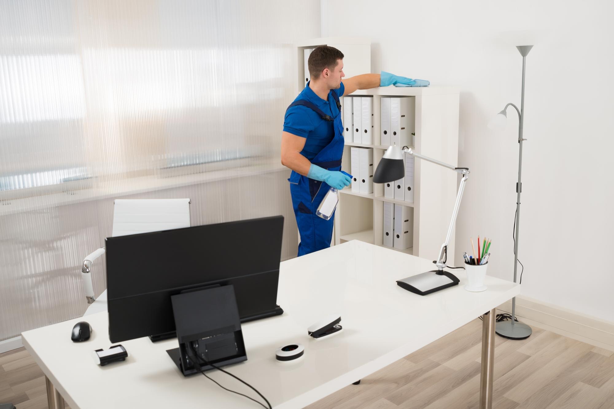 Effective Cleaning Strategies For Offices And Medical Facilities 2 mid adult male worker cleaning shelf with spray an c91e6017fcba104f6748