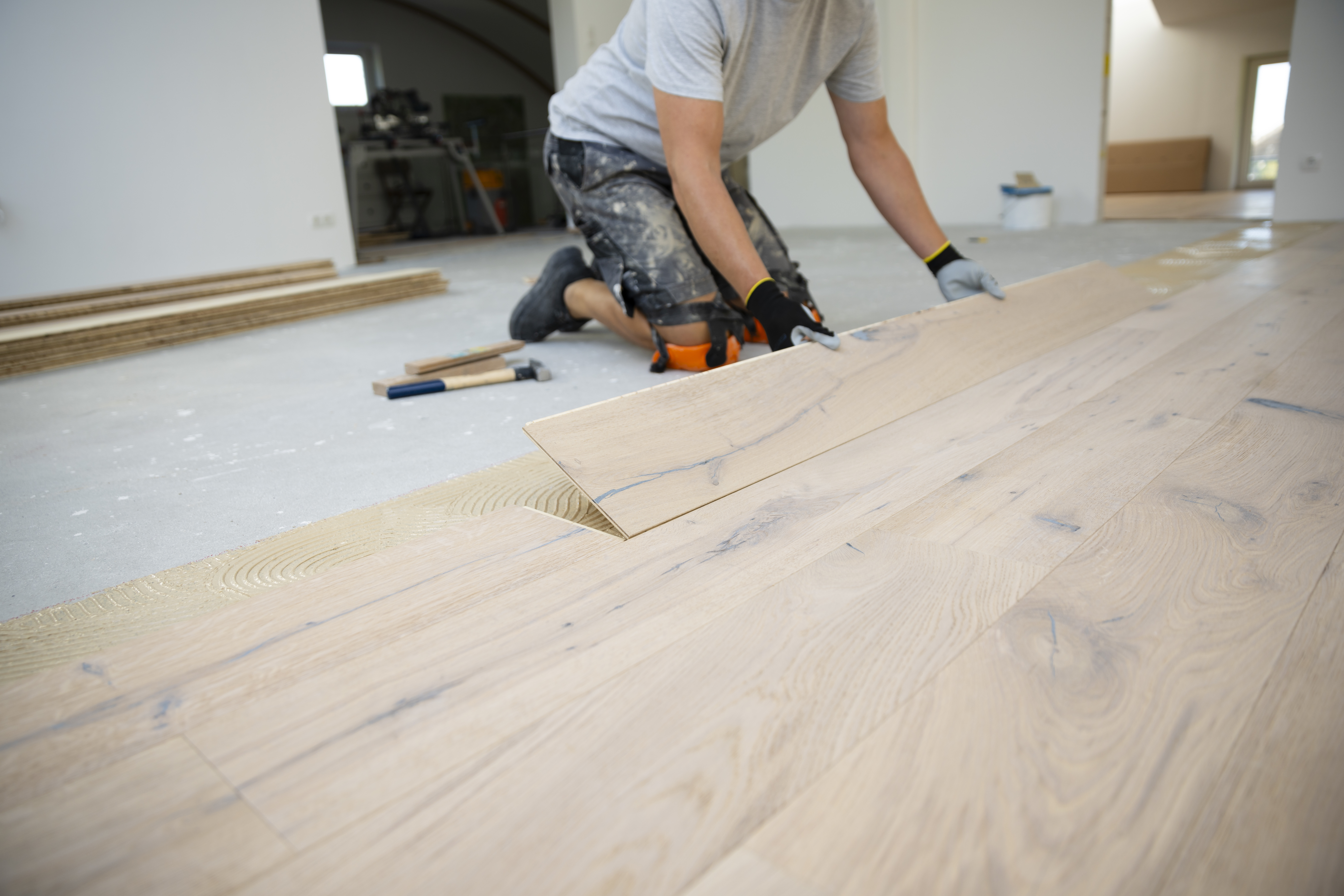 Middle aged man with gray hair glues lays parquet 890184fbc40454211aa7
