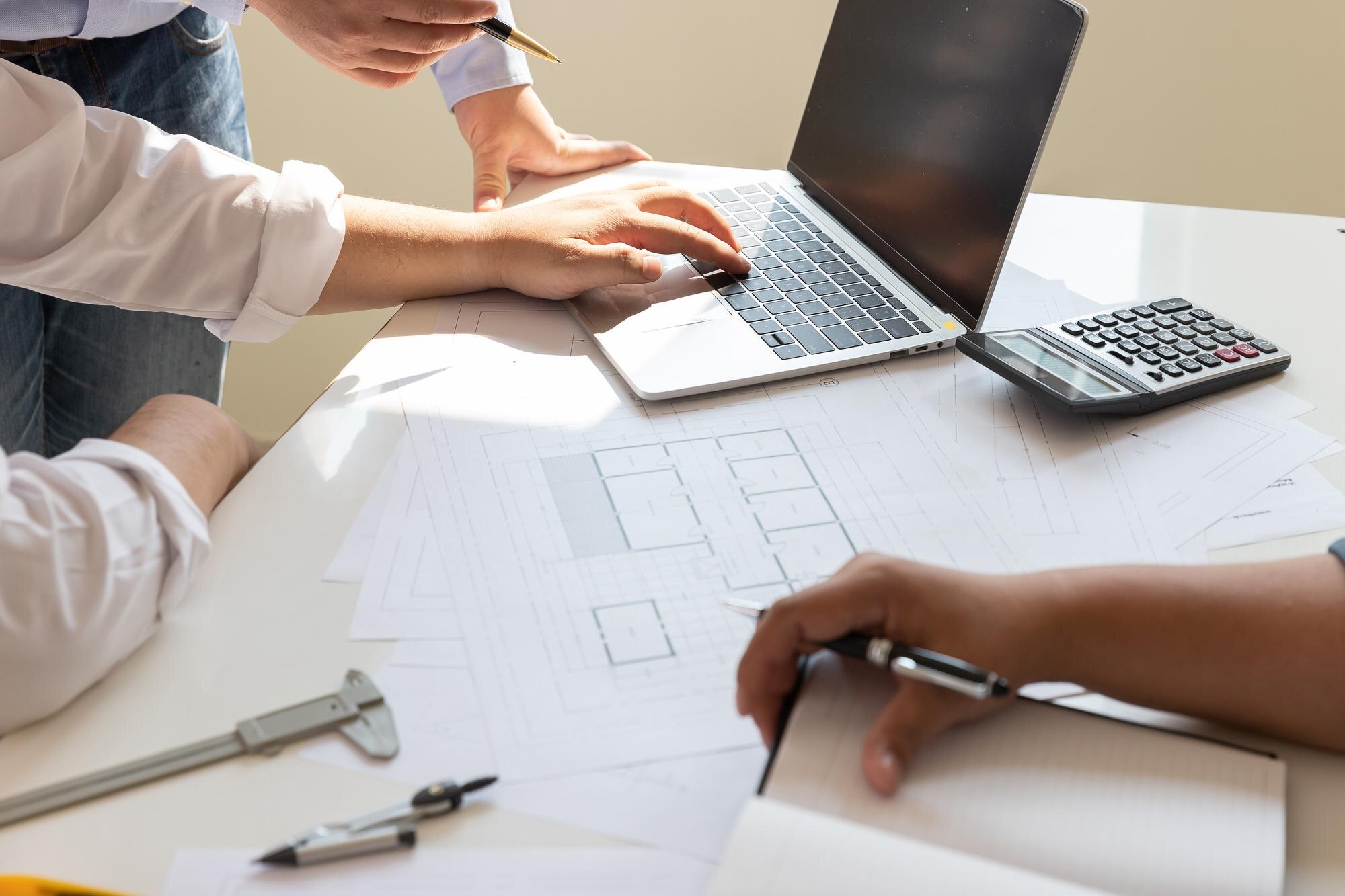 Midsection view of civil engineers reviewing architectural blueprints and construction loan plans