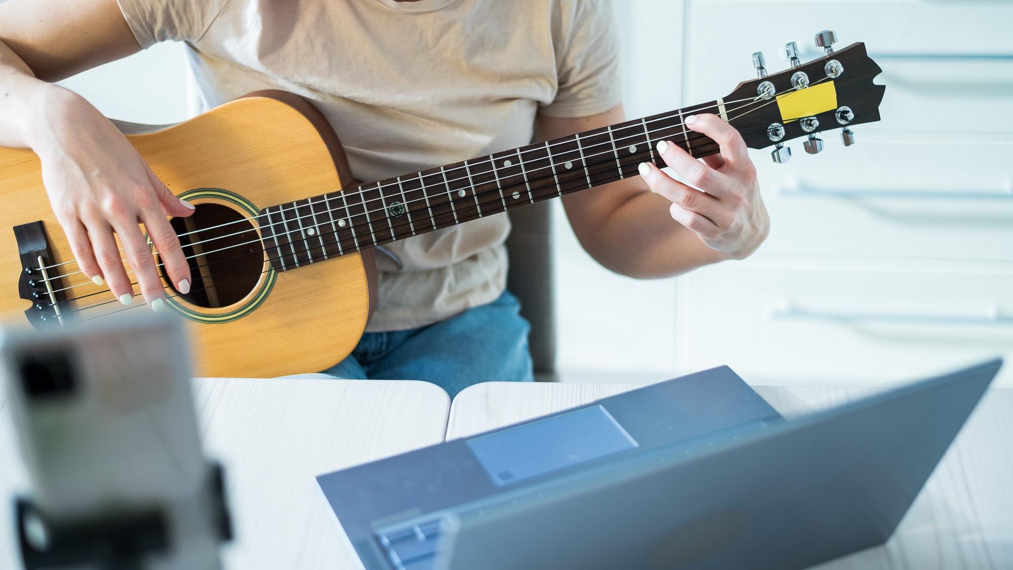 Guitarist practicing from web lessons on their computer.