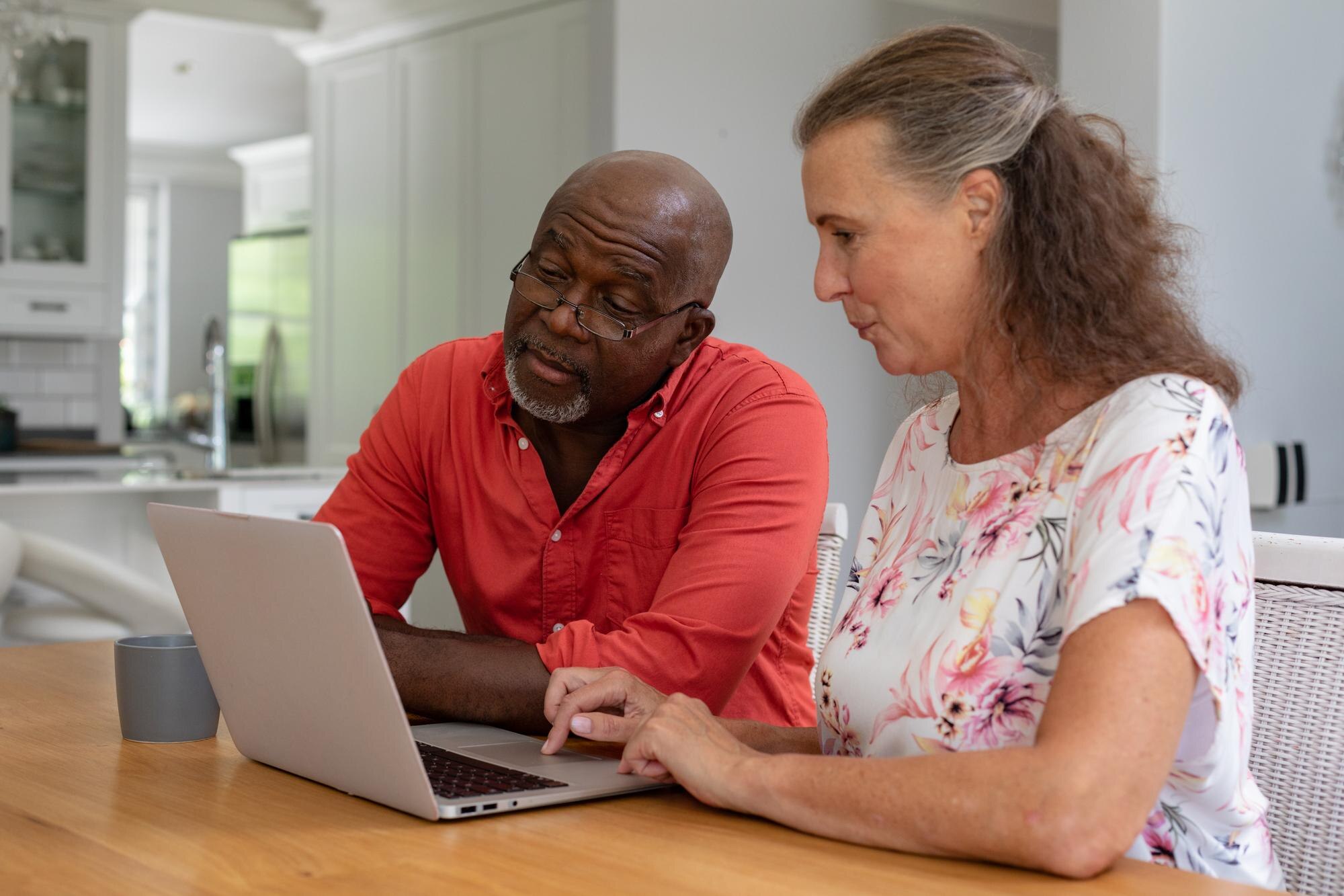 multiracial senior couple using laptop while sitti 633fa081e1e1ab4e8b2c